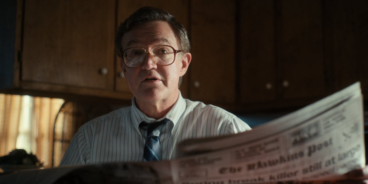 Joe Chrest as Ted Wheeler in Stranger Things Season 4. Ted looks up from his newspaper..