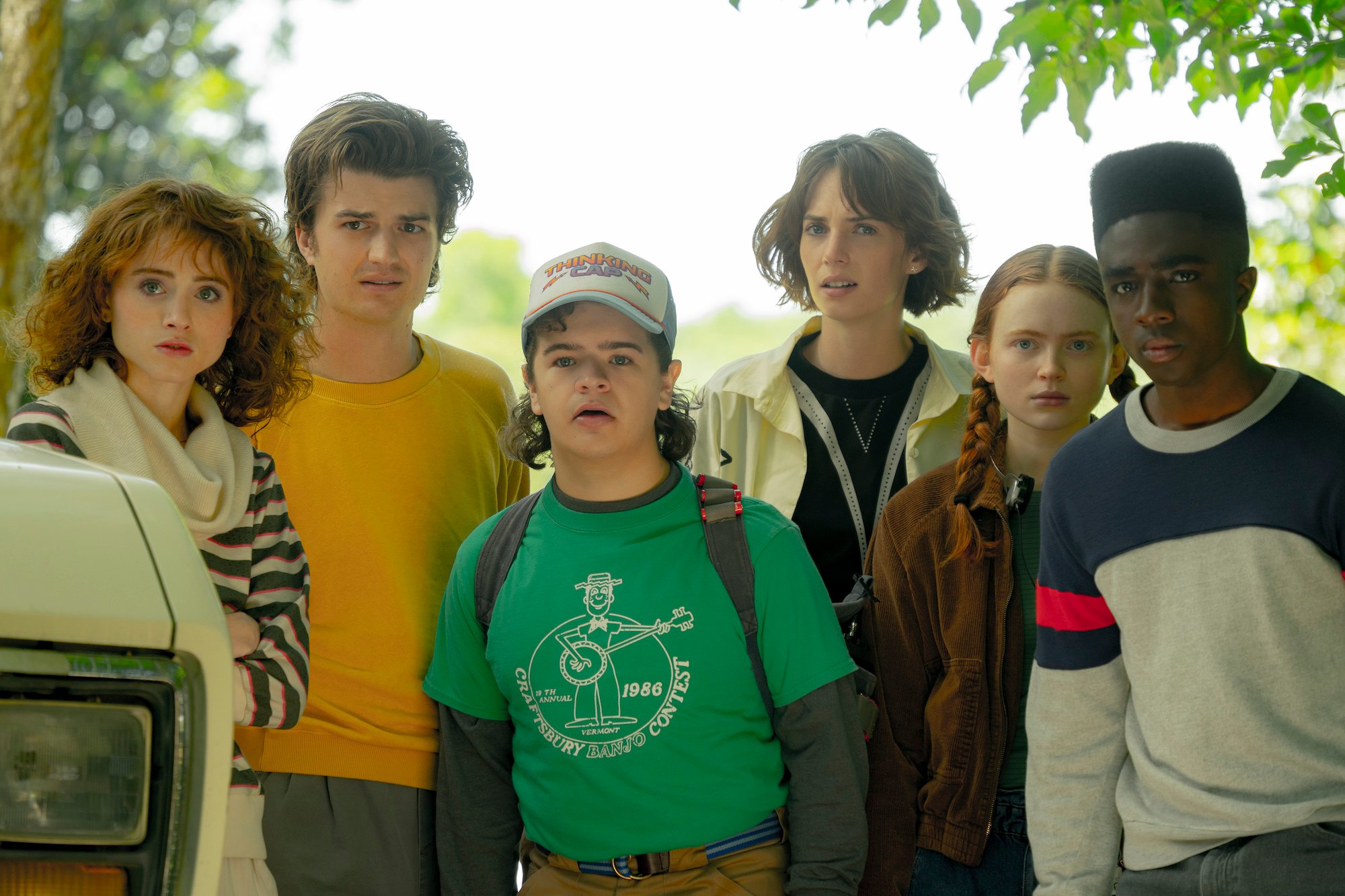 'Stranger Things' Season 5 will feature a time jump. In this 'Stranger Things 4' production stil, Natalia Dyer as Nancy Wheeler, Joe Keery as Steve Harrington, Gaten Matarazzo as Dustin Henderson, Maya Hawke as Robin Buckley, Sadie Sink as Max Mayfield, and Caleb McLaughlin as Lucas Sinclair stand looking at something off screen.