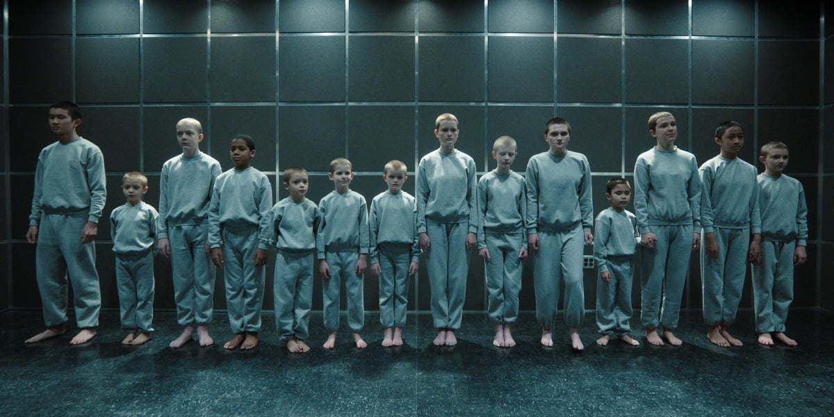 Children at Hawkins lab in Stranger Things have numbered tattoos. The children line up against a wall.