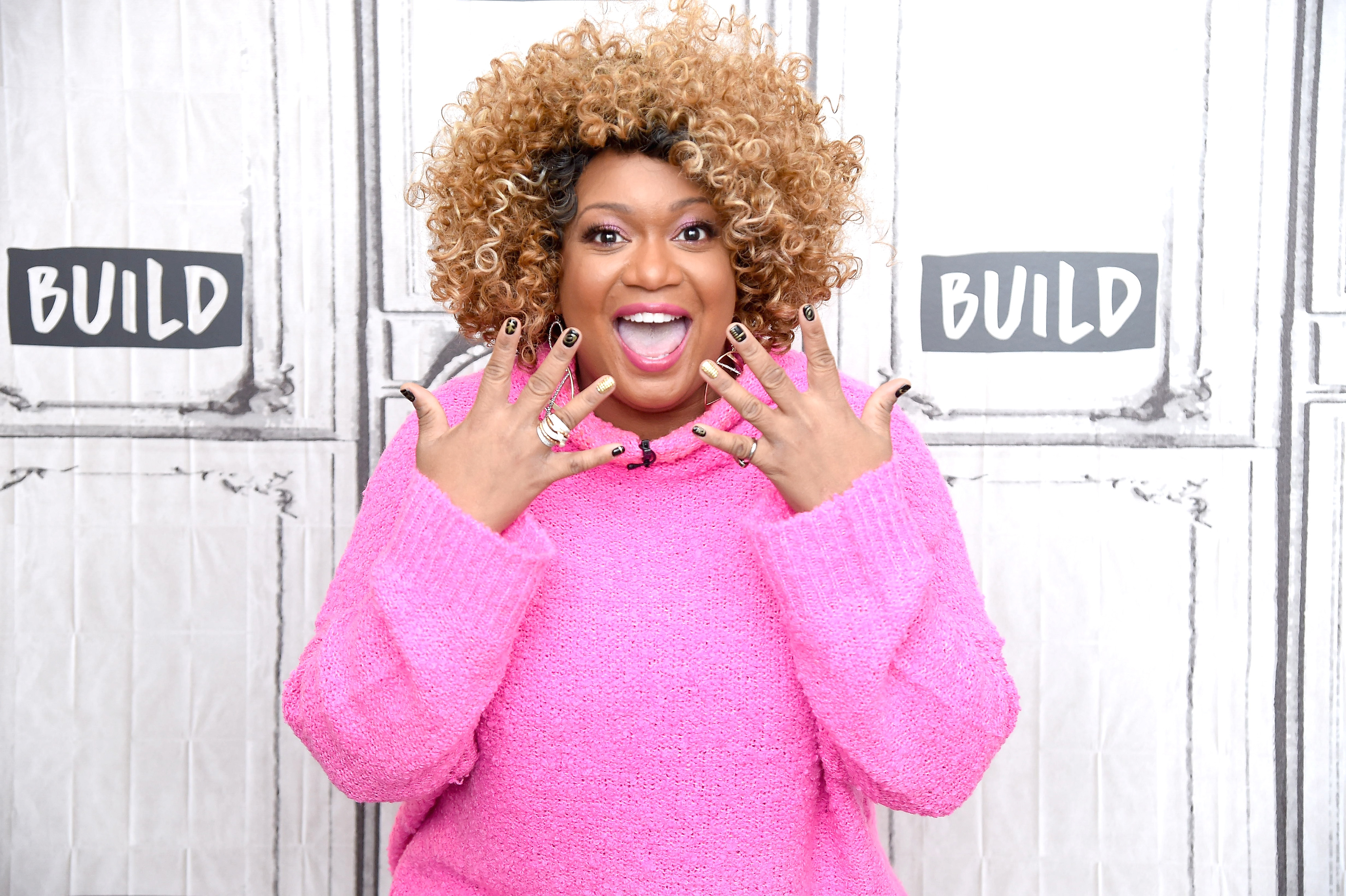 Celebrity chef Sunny Anderson wears a pink sweater in this photograph.