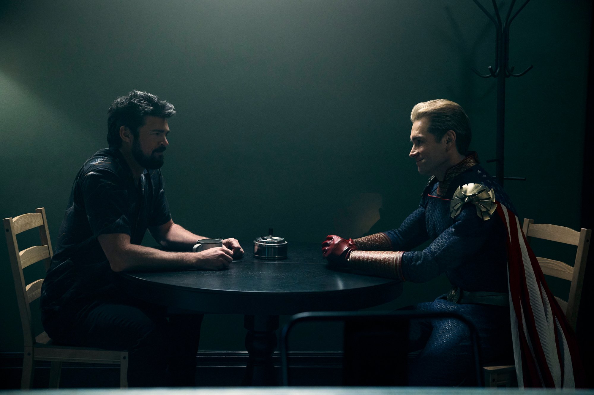 Karl Urban and Antony Starr as Billy Butcher and Homelander in 'The Boys' Season 3, which has an episode 4 release date of June 10. They're sitting across from one another at a table and staring.