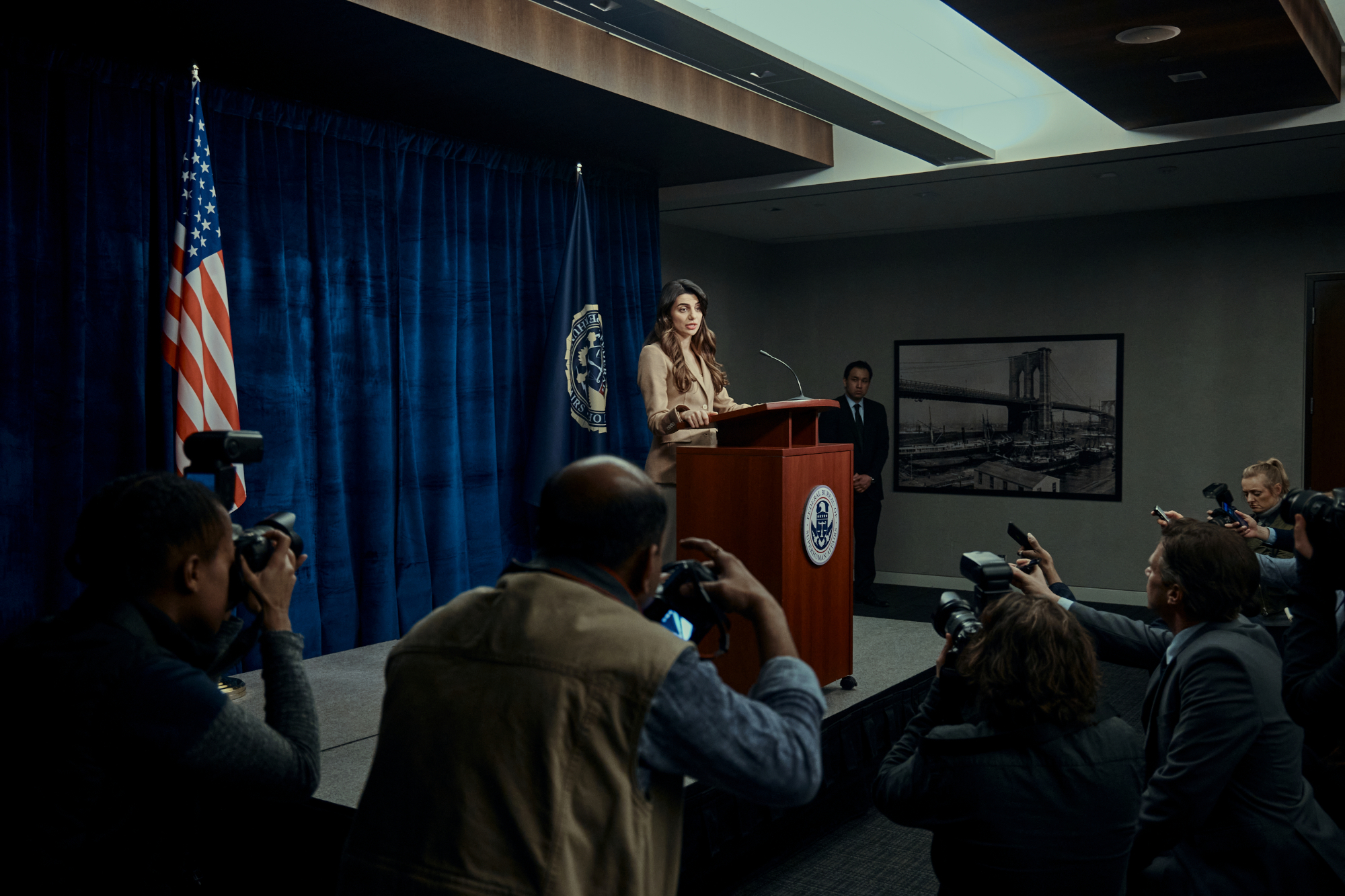 Claudia Doumit as Victoria Neuman in 'The Boys' Season 3, which has an episode 5 release date set for June 15. She's standing at a podium in front of a crowd and doing a press conference.