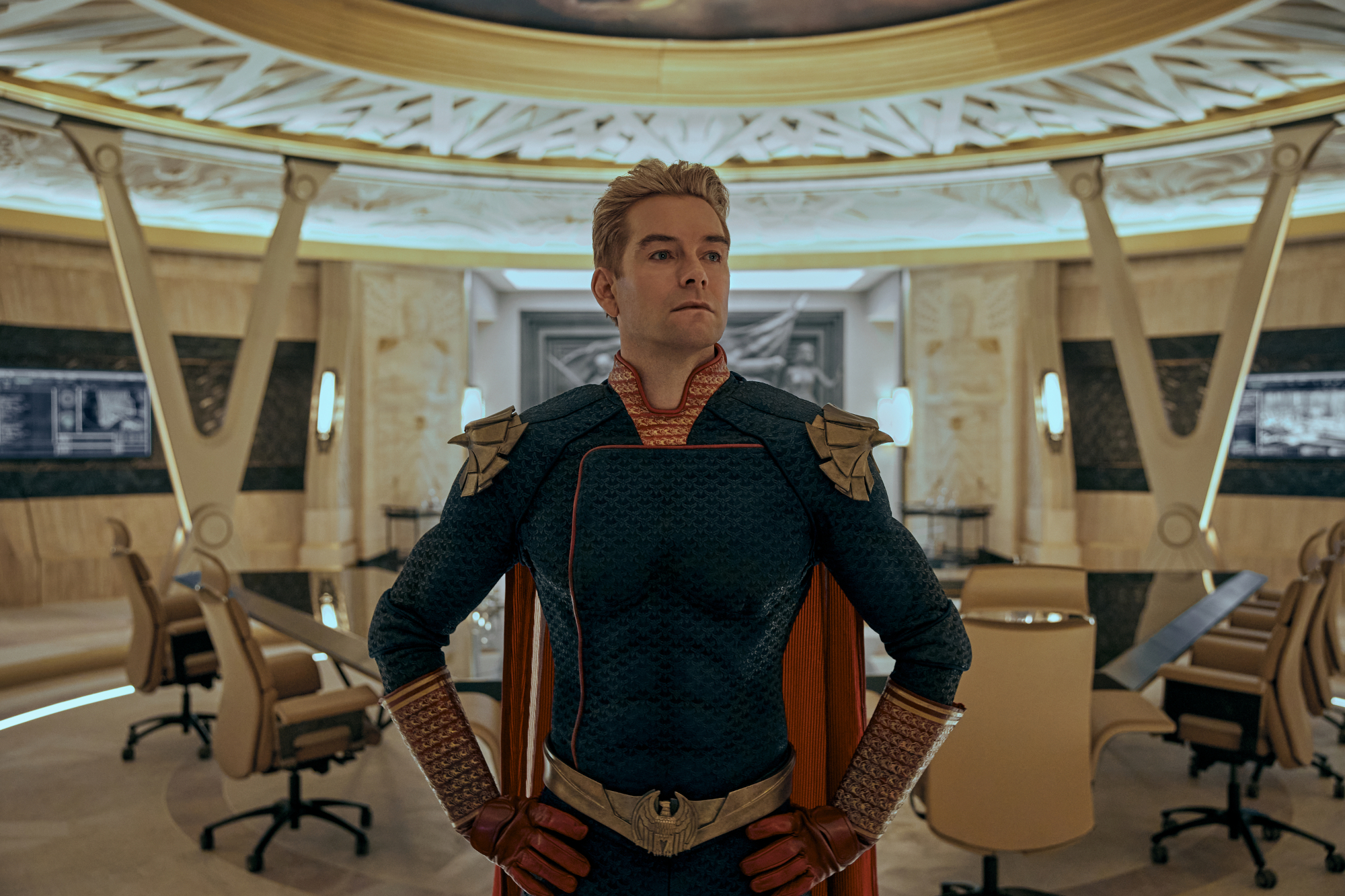 Antony Starr as Homelander in 'The Boys' Season 3, which Eric Kripke addressed the politics of. Homelander is standing in front of an empty conference room with his hands on his hips.