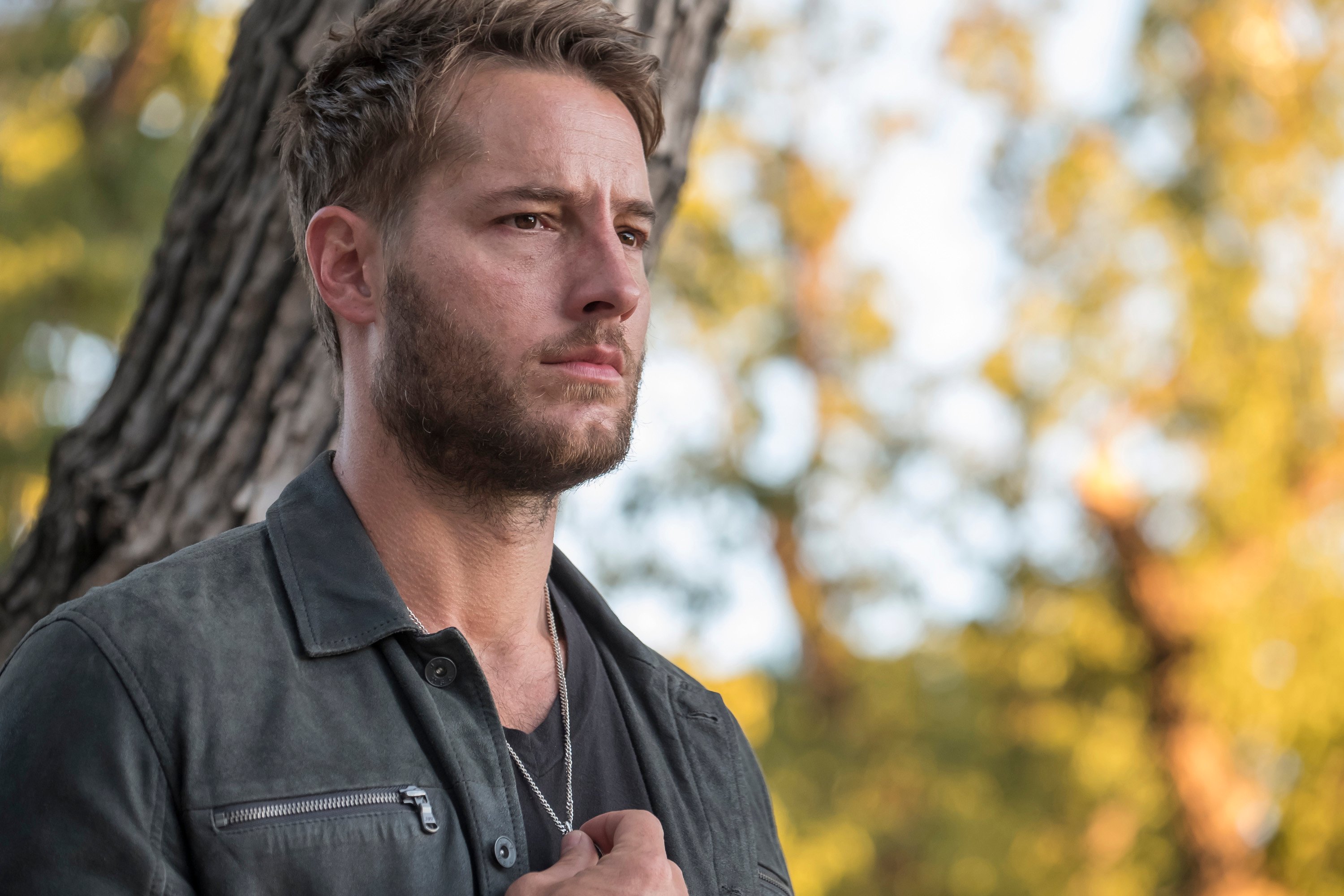 Justin Hartley, in character as Kevin Pearson in 'This Is Us' Season 2, wears a dark gray jacket over a gray shirt and necklace.