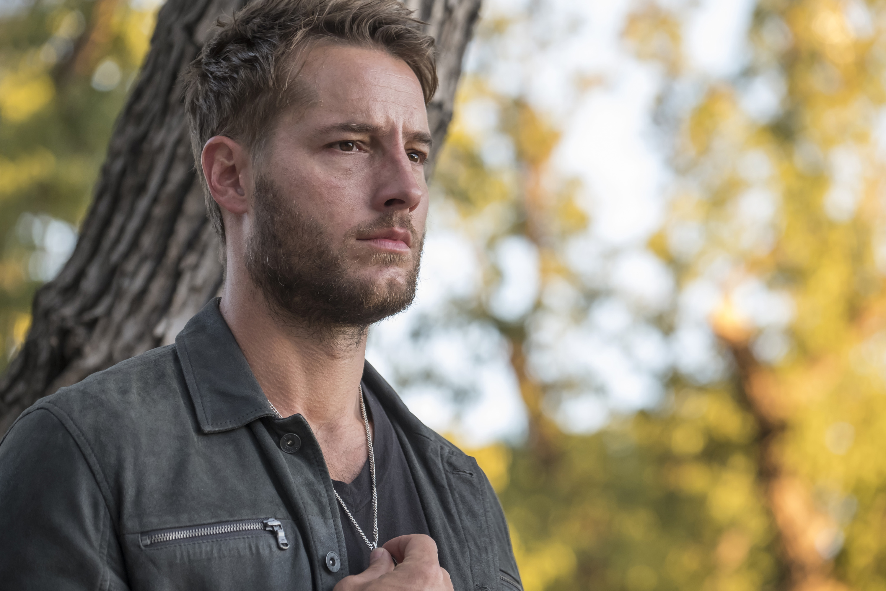 Justin Hartley, in character as Kevin Pearson in 'This Is Us' Season 2, wears a dark gray jacket over a gray shirt and necklace.