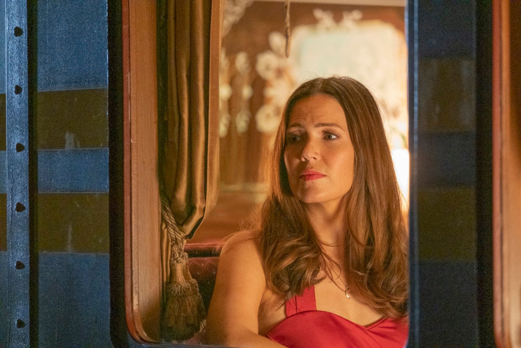 Mandy Moore as Rebecca Pearson in 'This Is Us' Season 6 Episode 17. She's wearing a red dress and staring out a window.