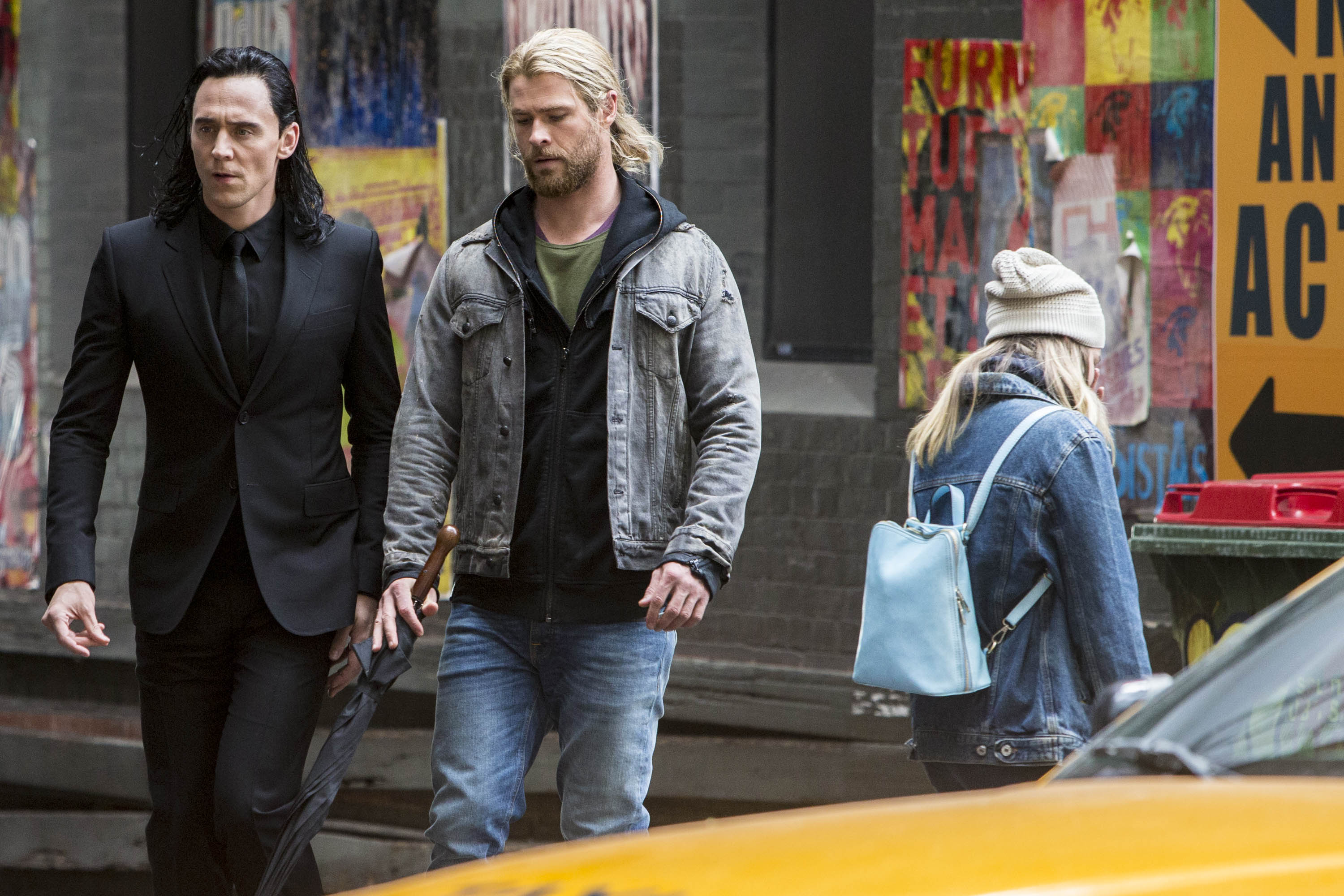 Tom Hiddleston, who some believe might be in 'Thor: Love and Thunder,' and Chris Hemsworth, in character as Loki and Thor, film a scene for 'Thor: Ragnarok.' Loki wears a black suit. Thor wears a jean jacket over a black hoodie over a green shirt and jeans.