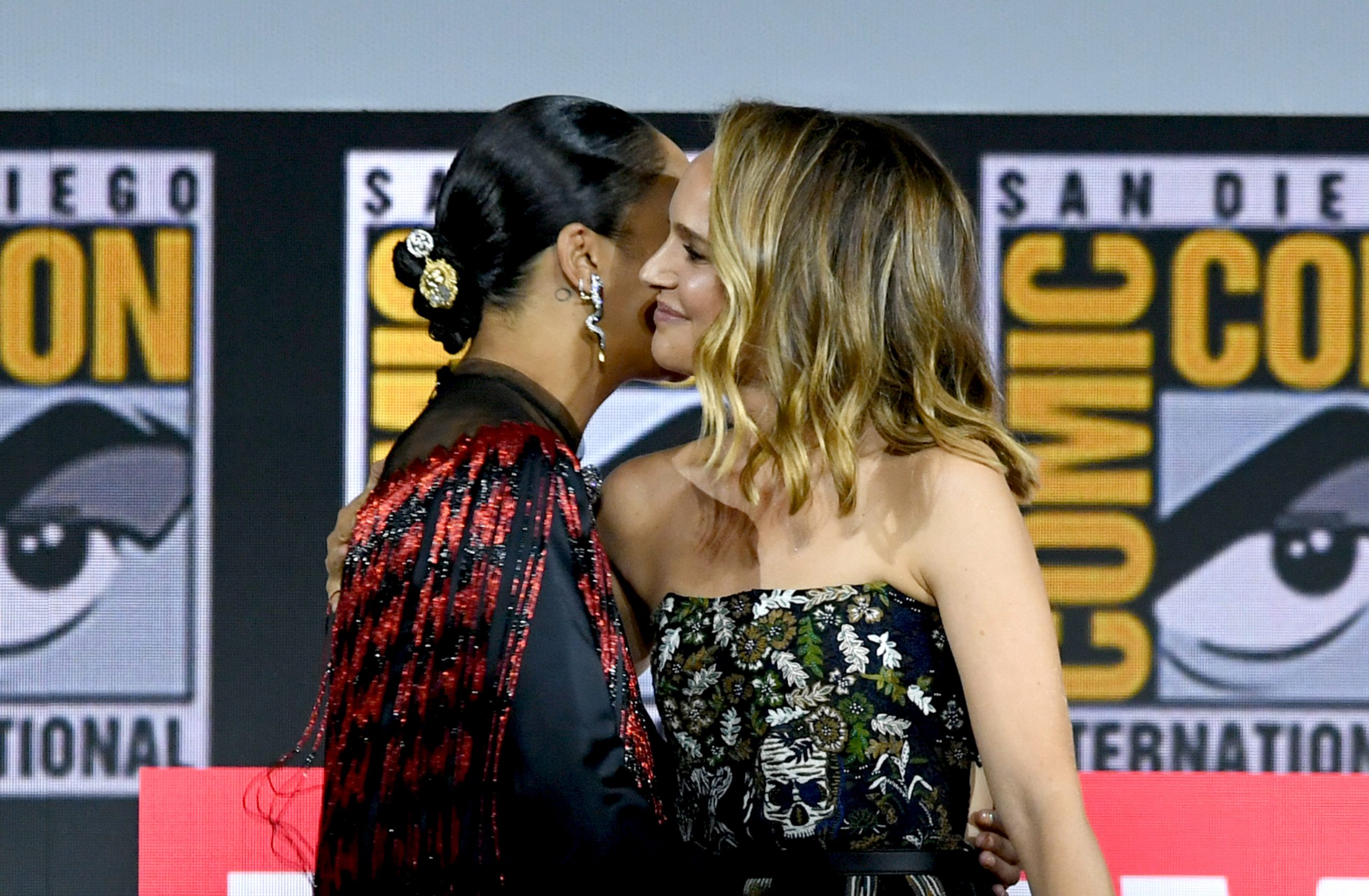 Tessa Thompson and Natalie Portman, who star in 'Thor: Love and Thunder,' embrace onstage at Comic-Con.
