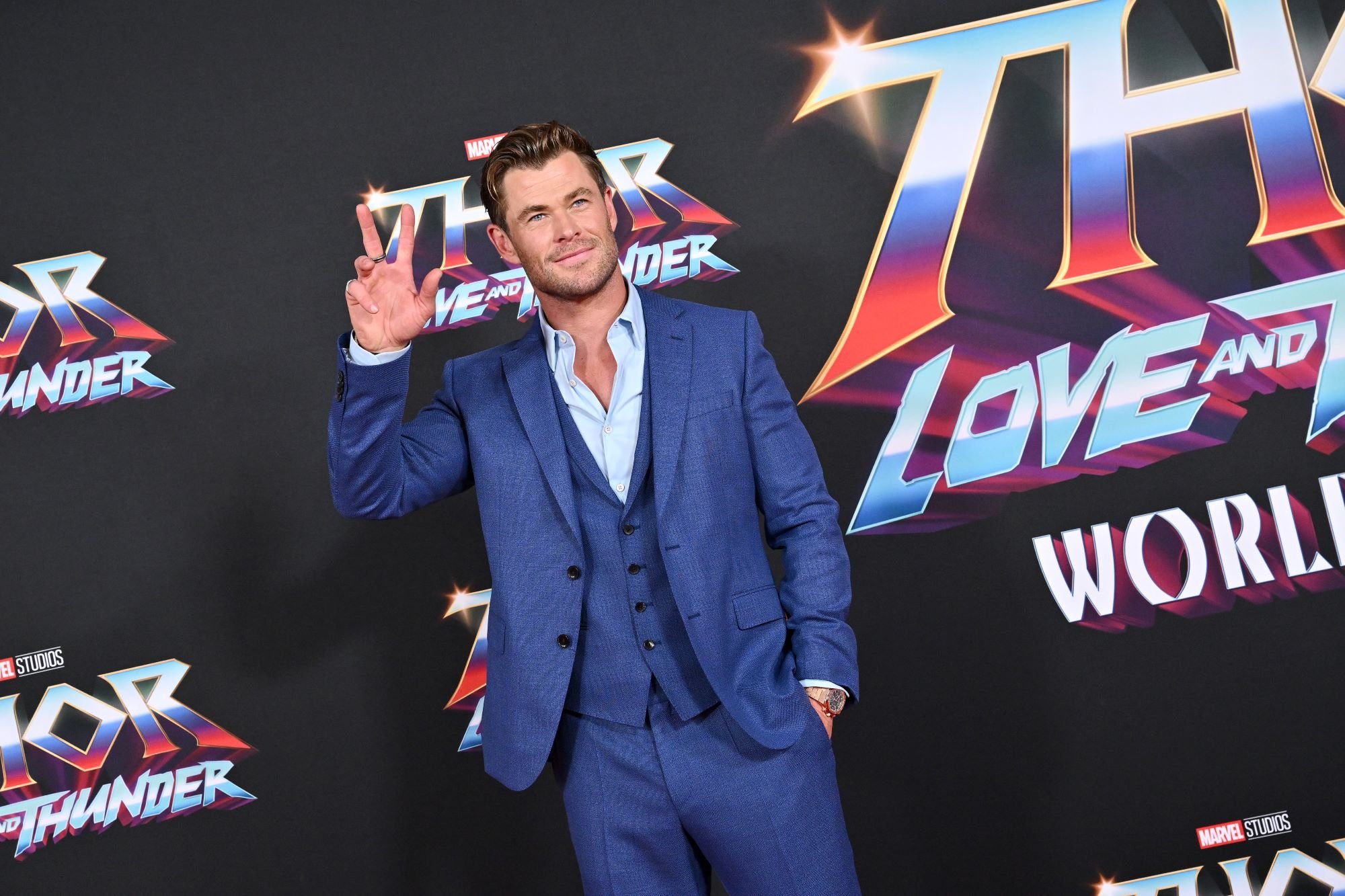 Chris Hemsworth attends the 'Thor: Love and Thunder' premiere, which brought about the first reactions to the Marvel movie, and he wears a blue suit while holding up a peace sign on the red carpet.