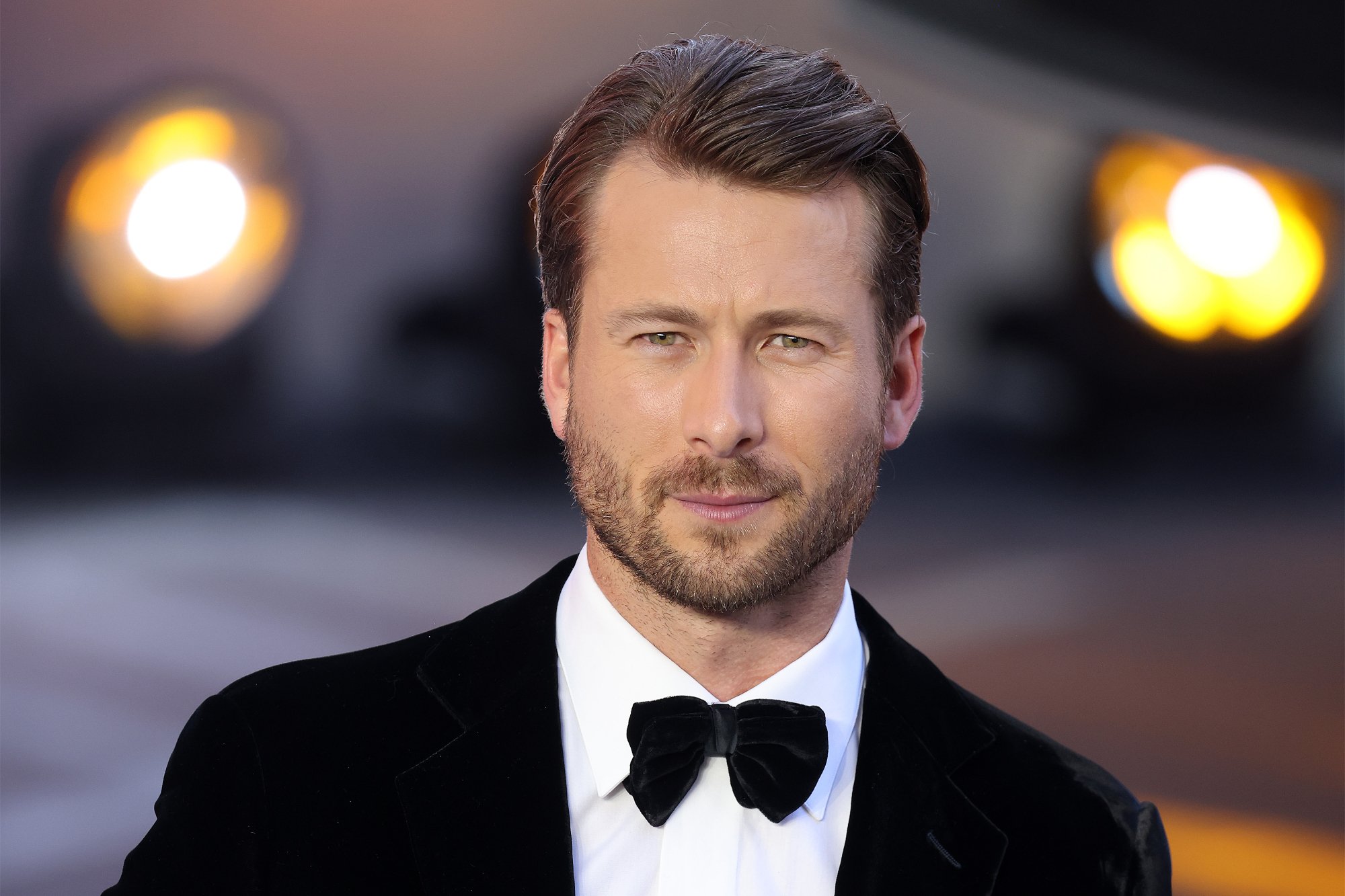 'Top Gun: Maverick' star Glen Powell, who plays Hangman wearing a tuxedo with blurred out lights in the background