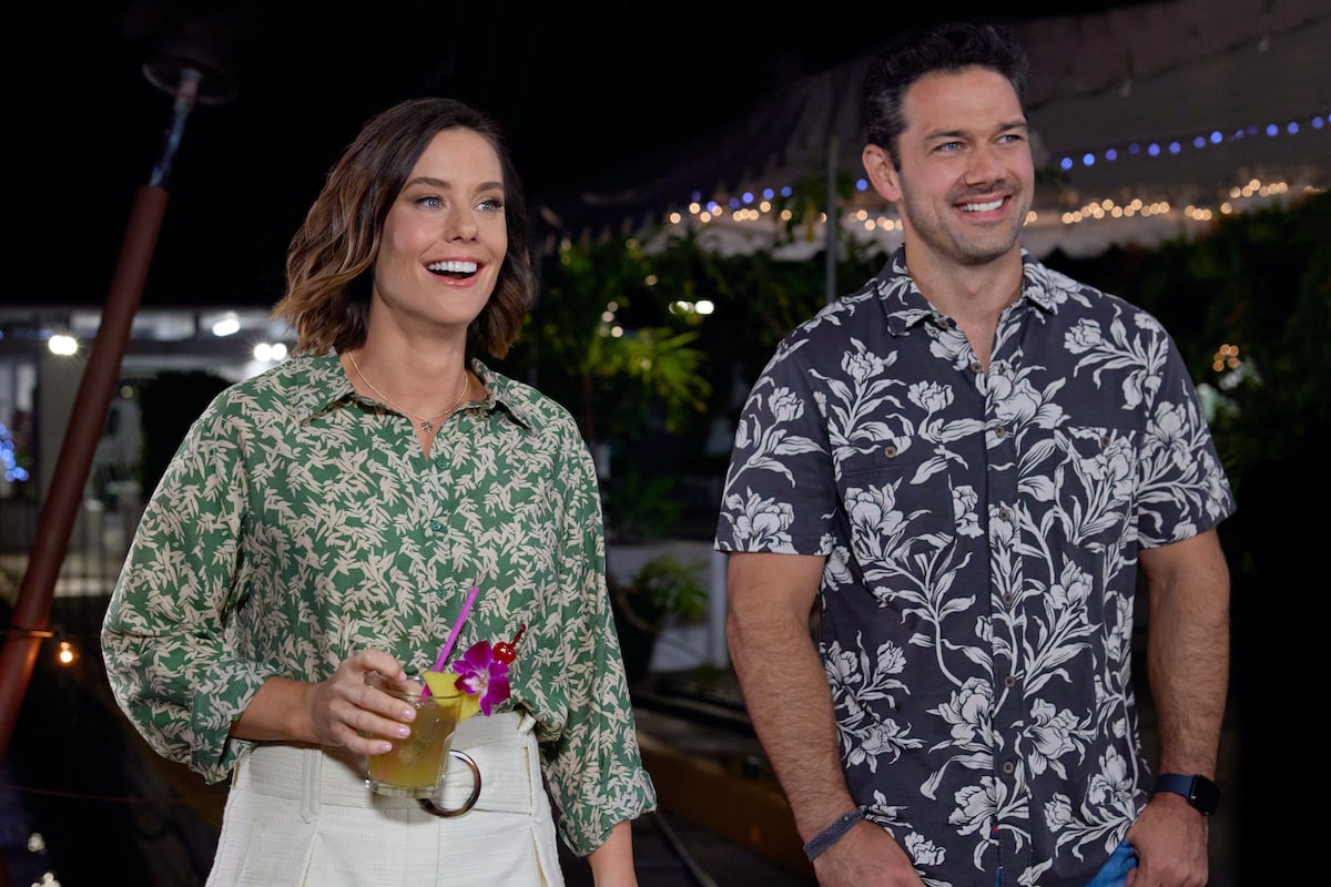 Ashley Williams and Ryan Paevey, both wearing Hawaiian print shirts, in the Hallmark movie 'Two Tickets to Paradise'