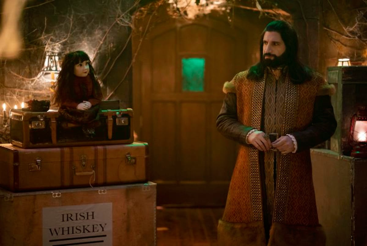 Kayvan Novak as Nandor in What We Do in the Shadows Season 4. Nandor stares at a creepy doll.