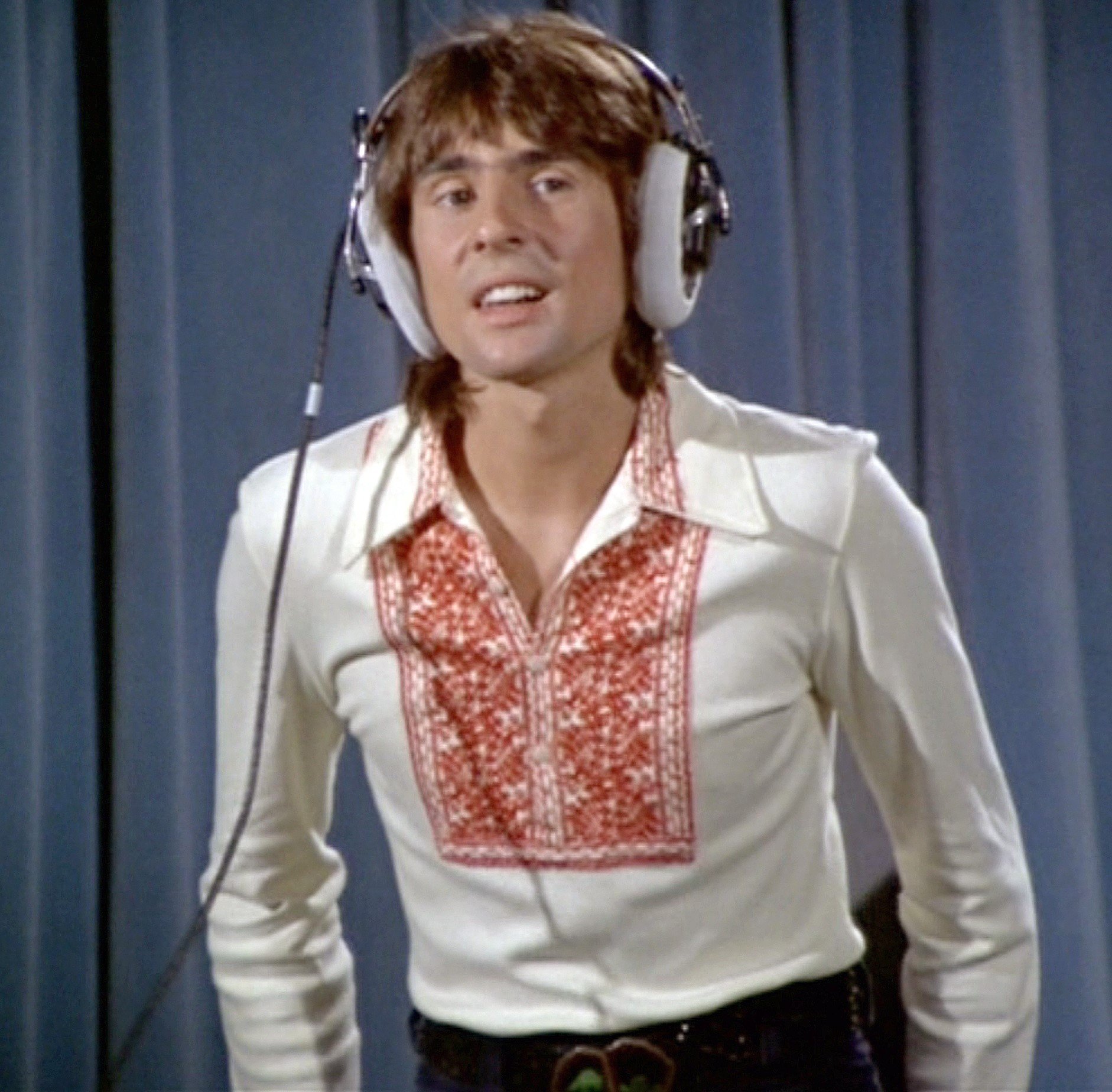 The Monkees' Davy Jones in front of a blue curtain