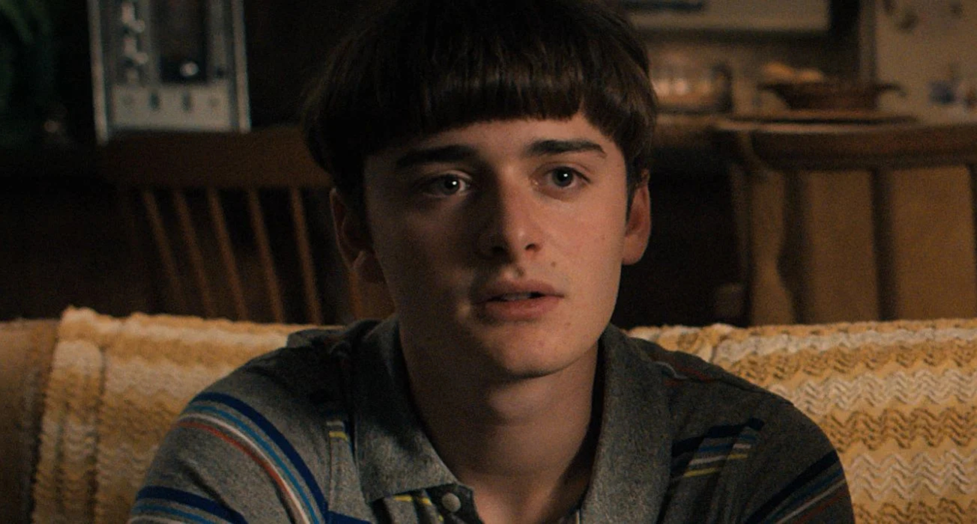 Will Byers in 'Stranger Things' Season 4 in relation to his sexuality sitting on couch.