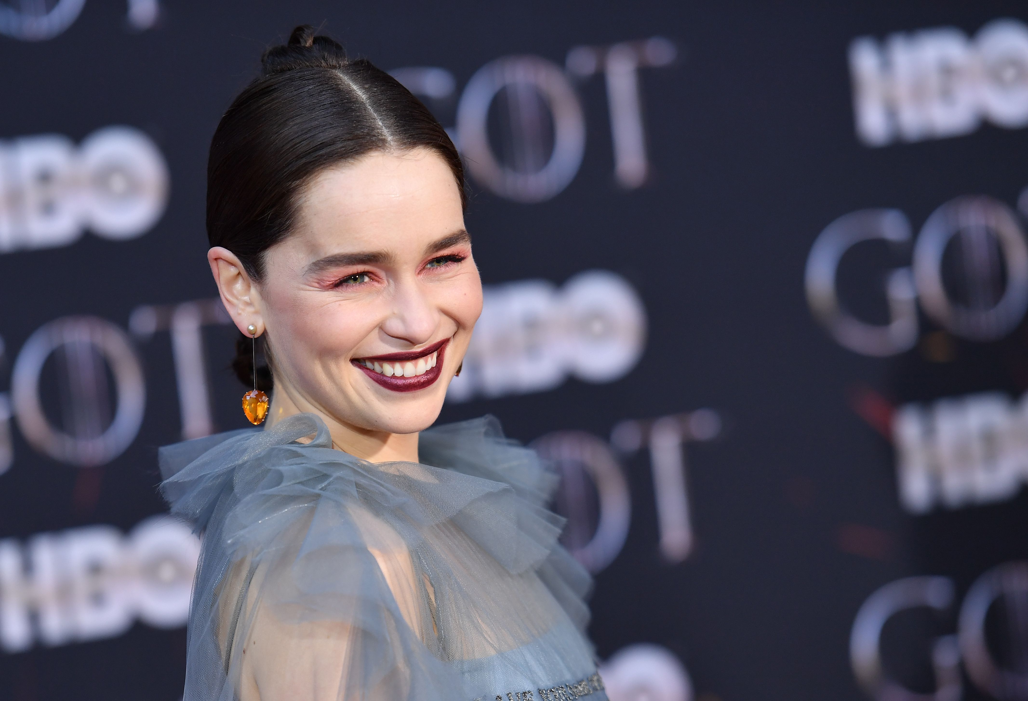 Emilia Clarke poses in front of a 'Game of Thrones' step and repeat