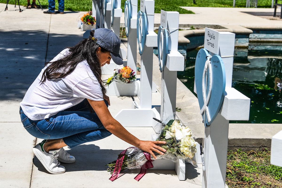 Meghan Markle places flowers in front of a row of white crosses with blue hearts at a school shooting memorial in Uvalde, Texas. 