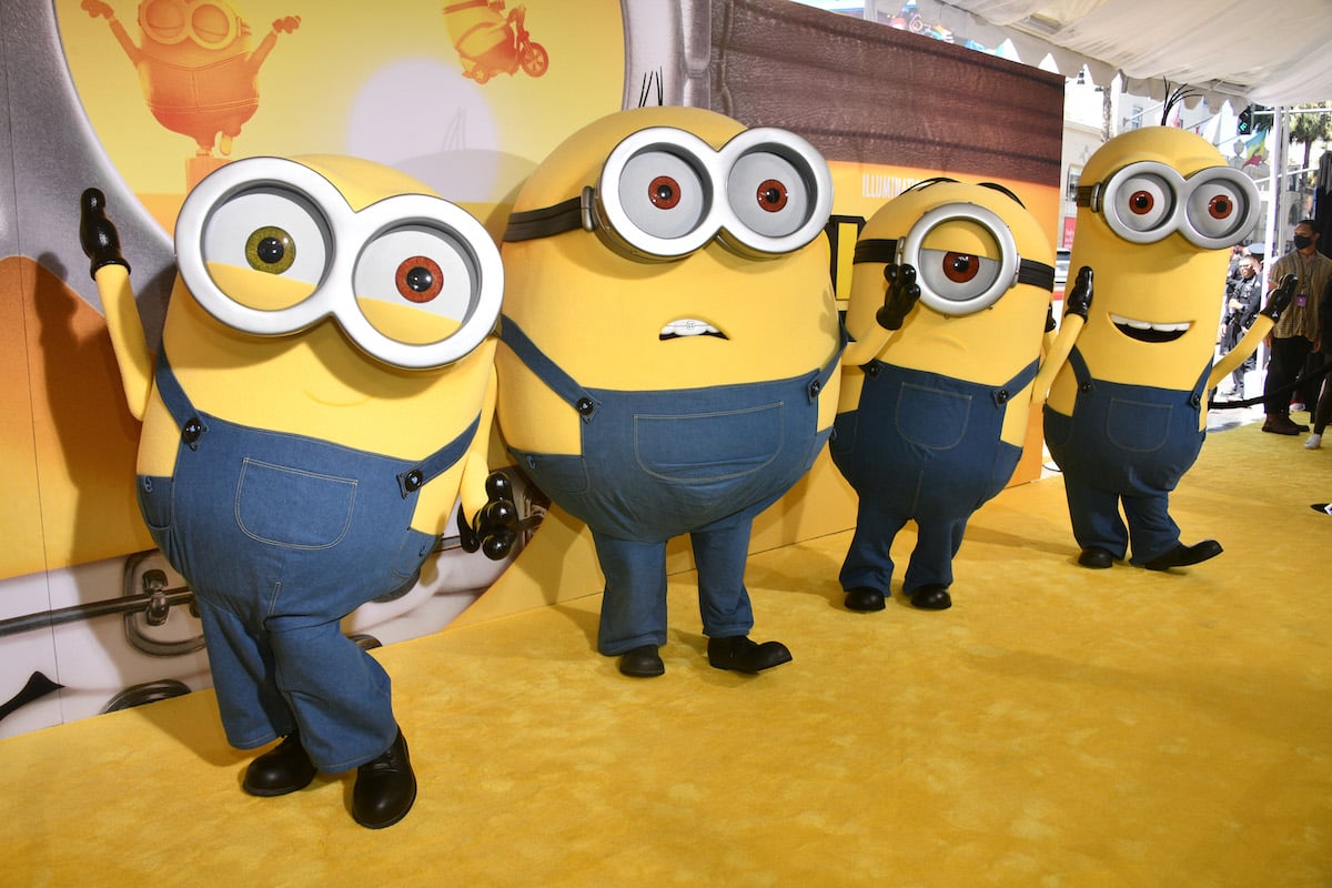 Actors in costume portraying Minions Bob, Otto, Stuart, and Dave represent some of the Minions: The Rise of Gru cast at the movie premiere in Hollywood, posing on the yellow carpet