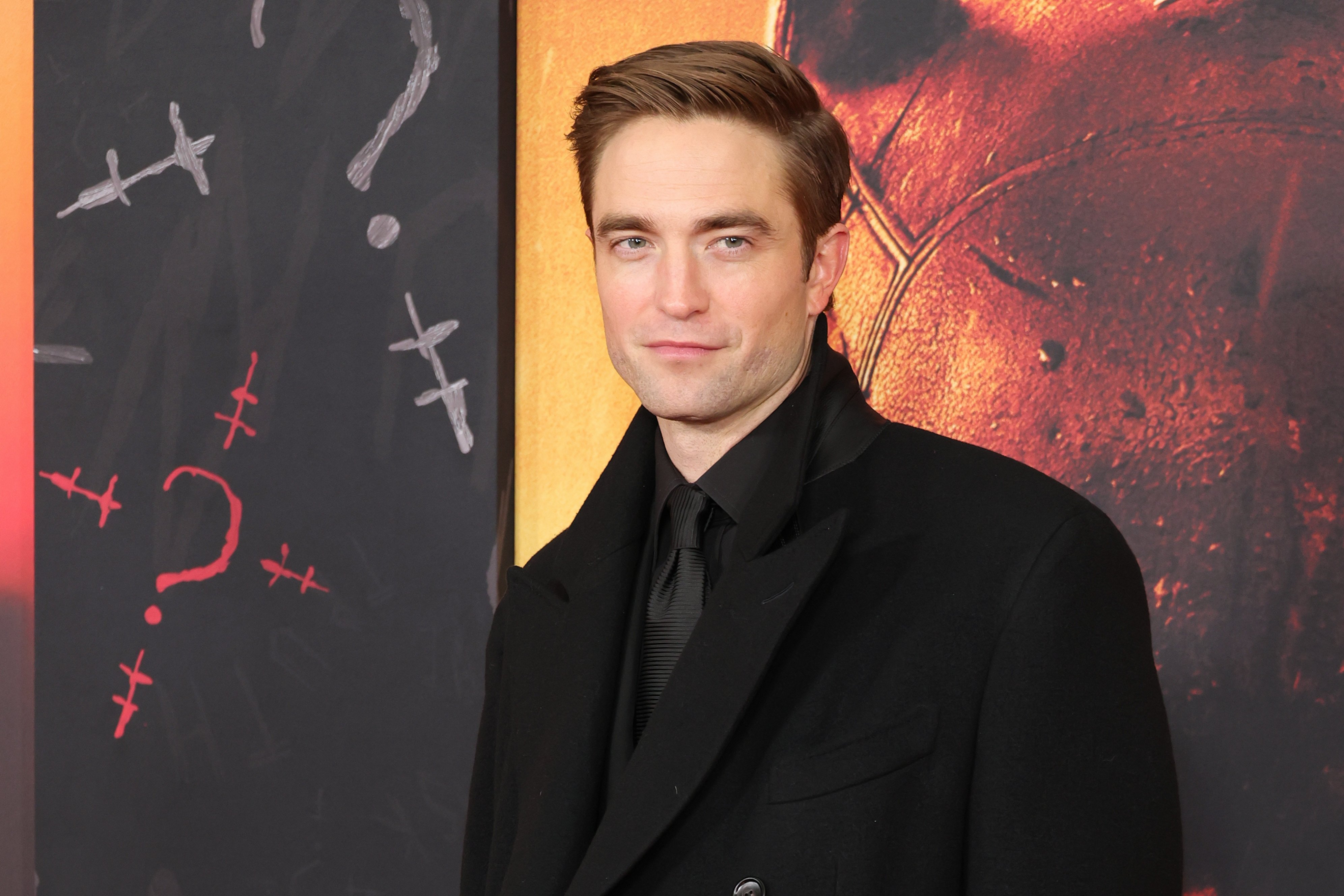 a closeup of Robert Pattinson's face and shoulders as he poses at 'The Batman' premiere