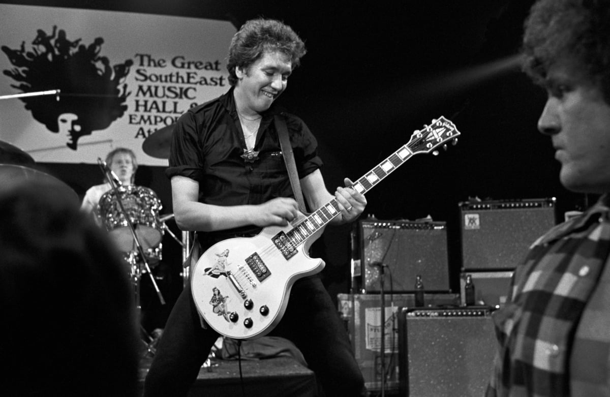 Steve Jones plays guitar on stage as a member of the Sex Pistols.