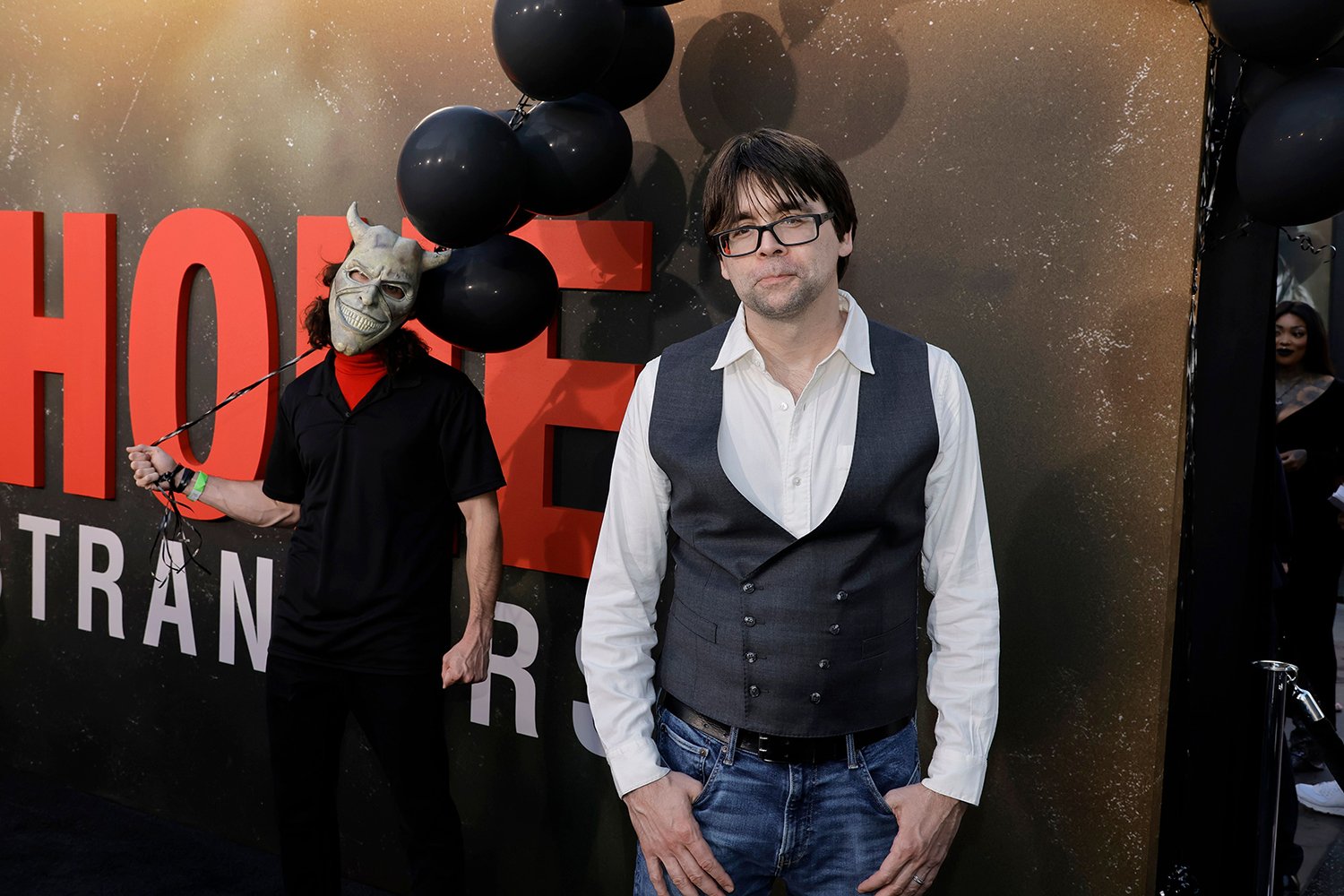 Joe Hill attends the premiere of The Black Phone as The Grabber stands behind him with balloons