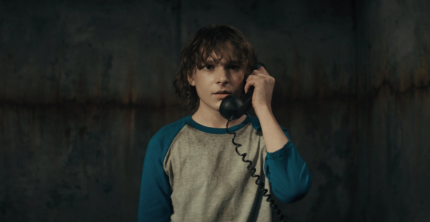 Mason Thames as Finney Shaw answering the phone in The Black Phone, which is not based on a true story.