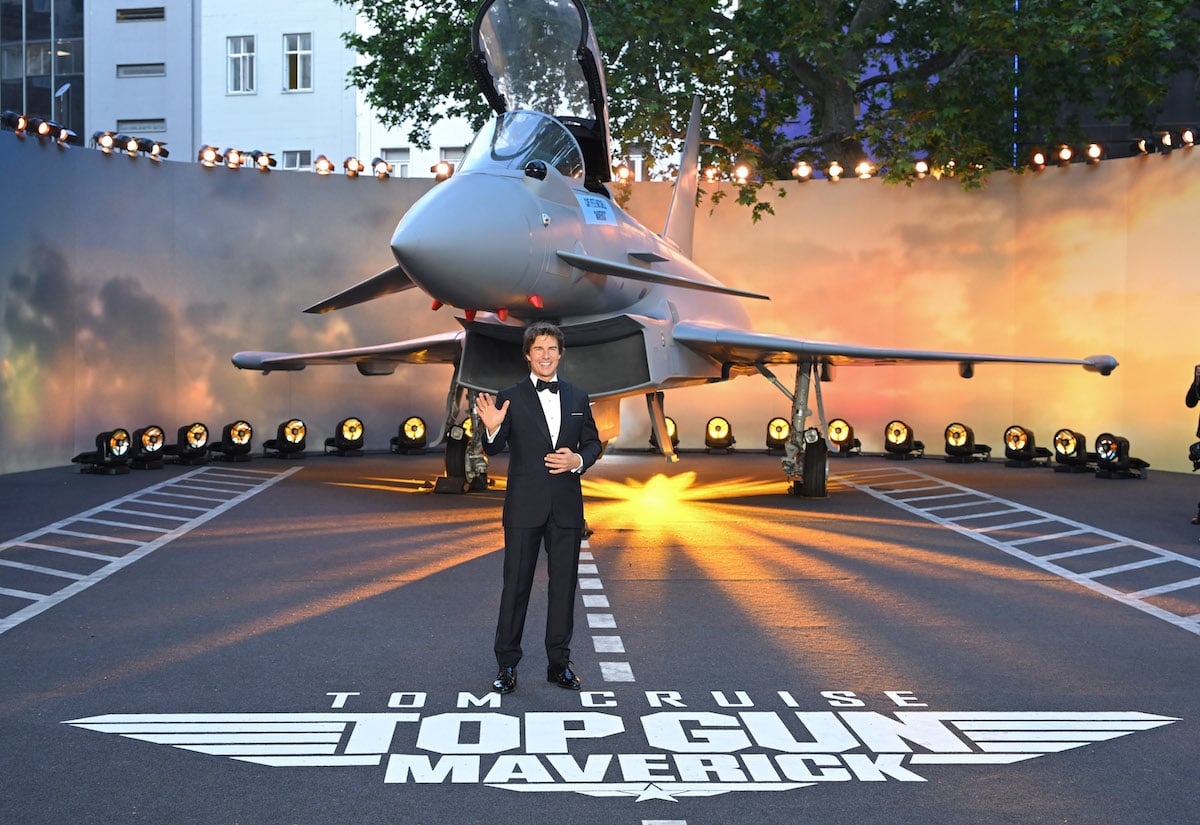 Tom Cruise waves in front of a plane at the Top Gun: Maverick movie premiere.