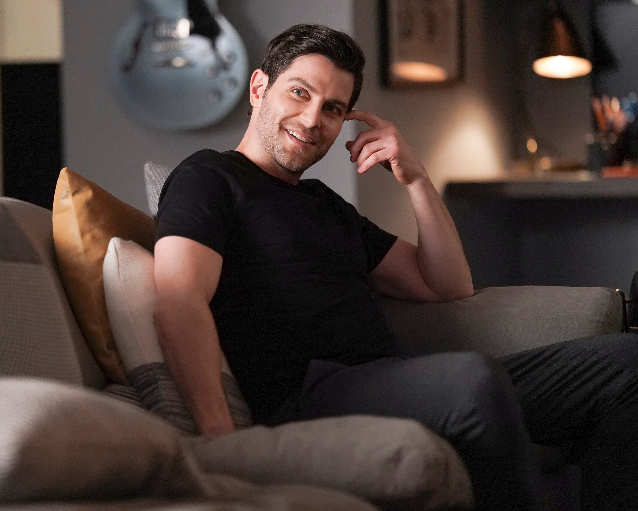 'A Million Little Things' David Giuntoli as Eddie Saville sitting on the couch smiling