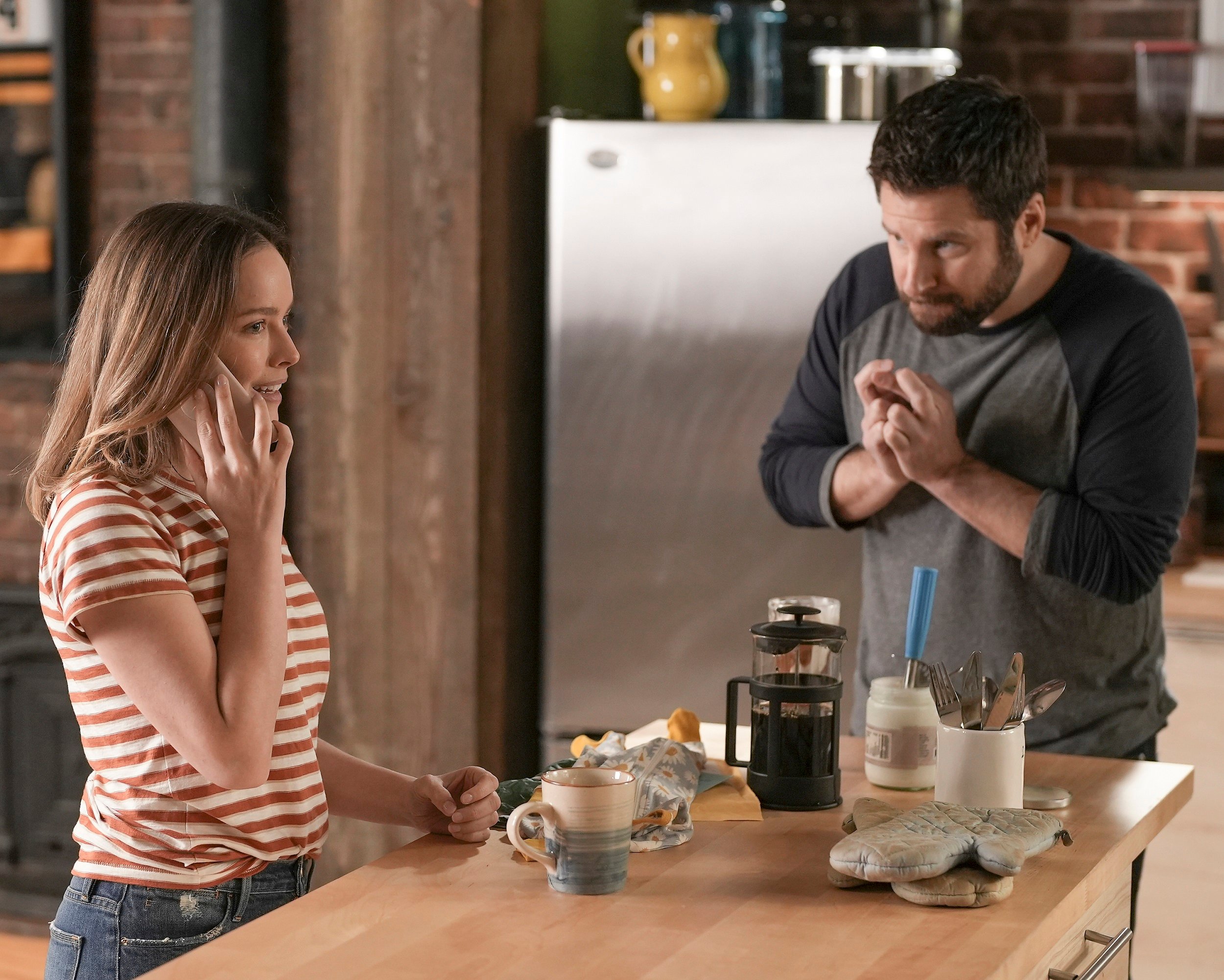 'A Million Little Things' Season 4 Allison Miller as Maggie Bloom on the phone and James Roday Rodriguez as Gary Mendez crossing his fingers