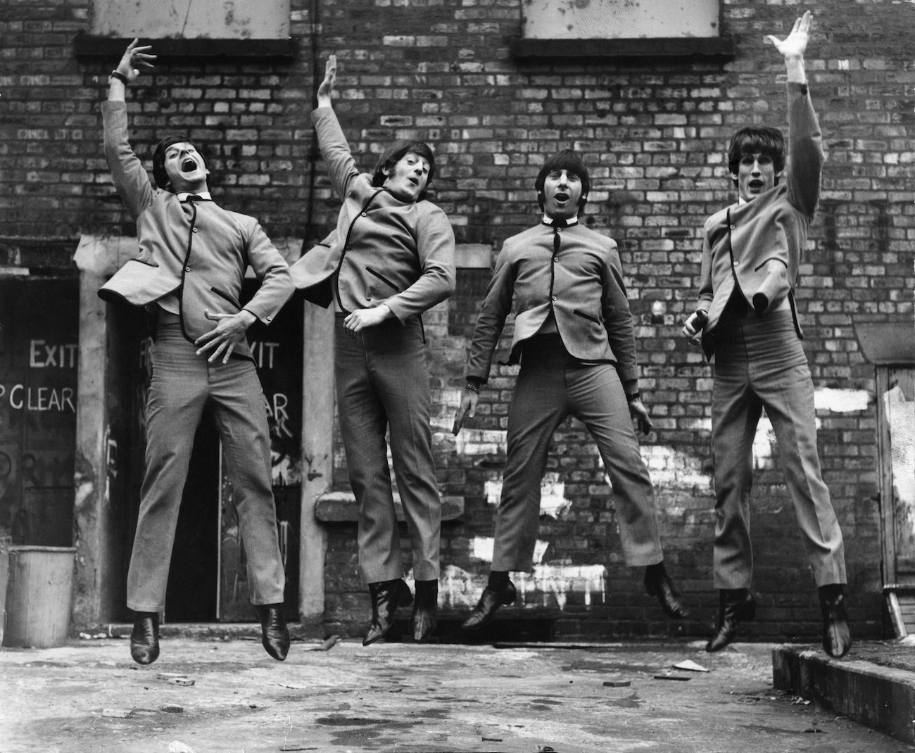 Actors in the 1974 musical, 'John, Paul, George, Ringo, and Bert' jumping in the air wearing Beatle suits.