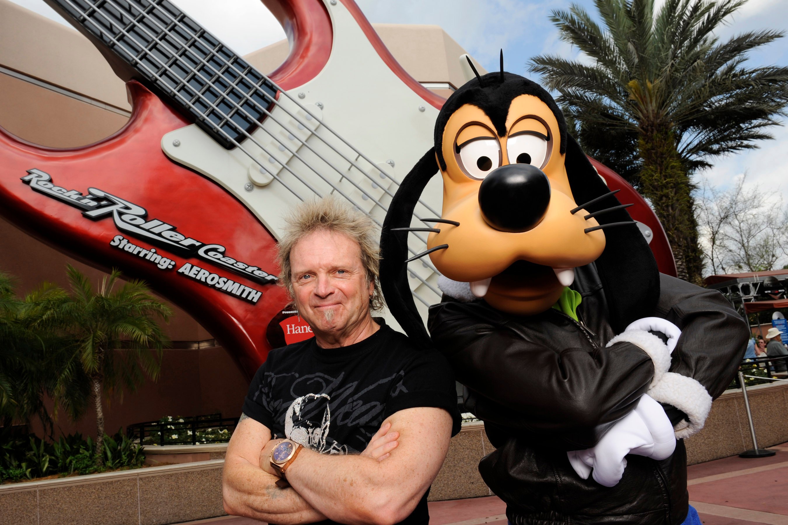 Aerosmith drummer Joey Kramer poses with Disney character Goofy at Disney's Hollywood Studios in front of the 'Rock 'n' Roller Coaster Starring Aerosmith'