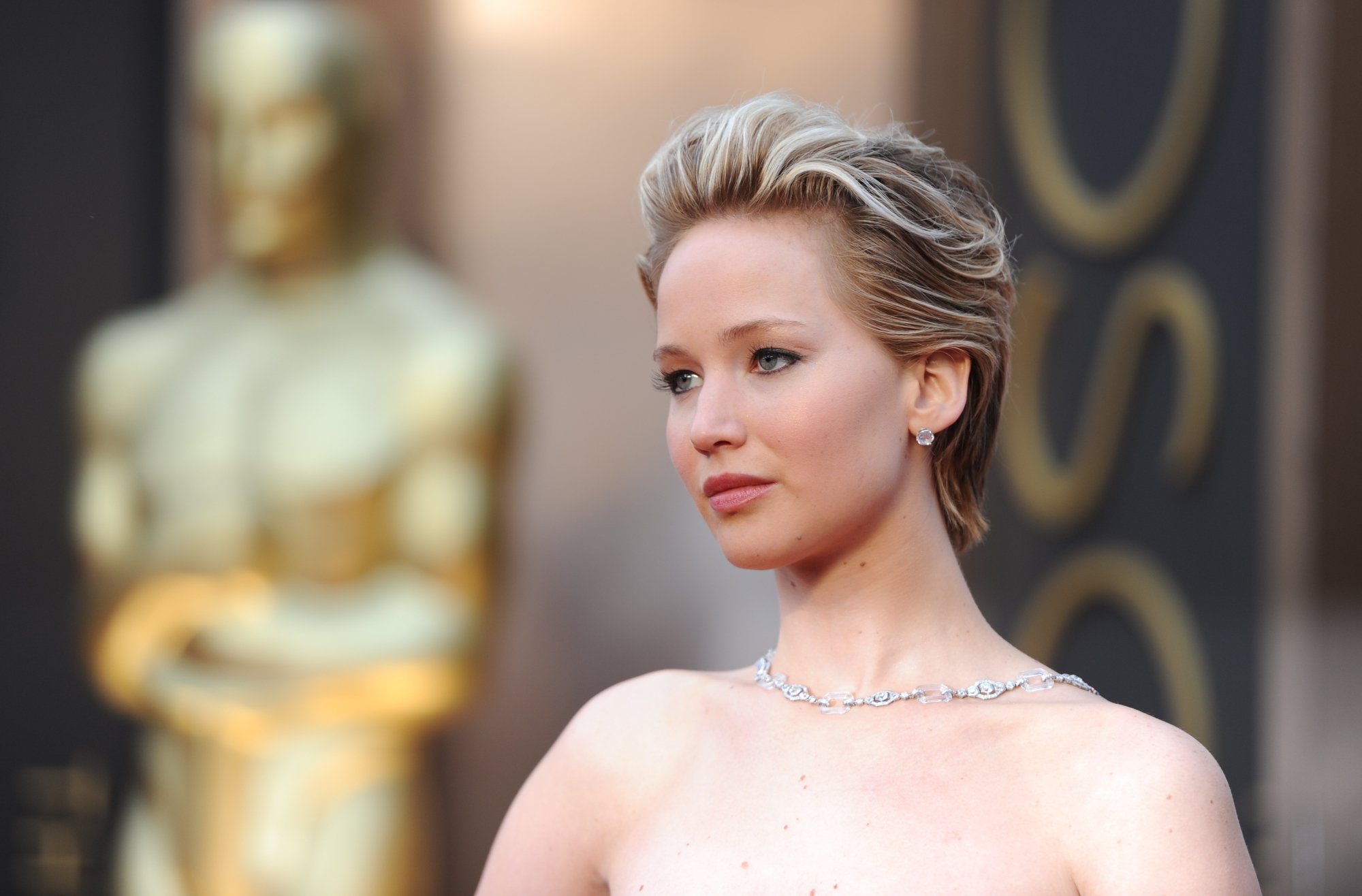 'American Hustle' actor Jennifer Lawrence standing in front of an Oscar award statue