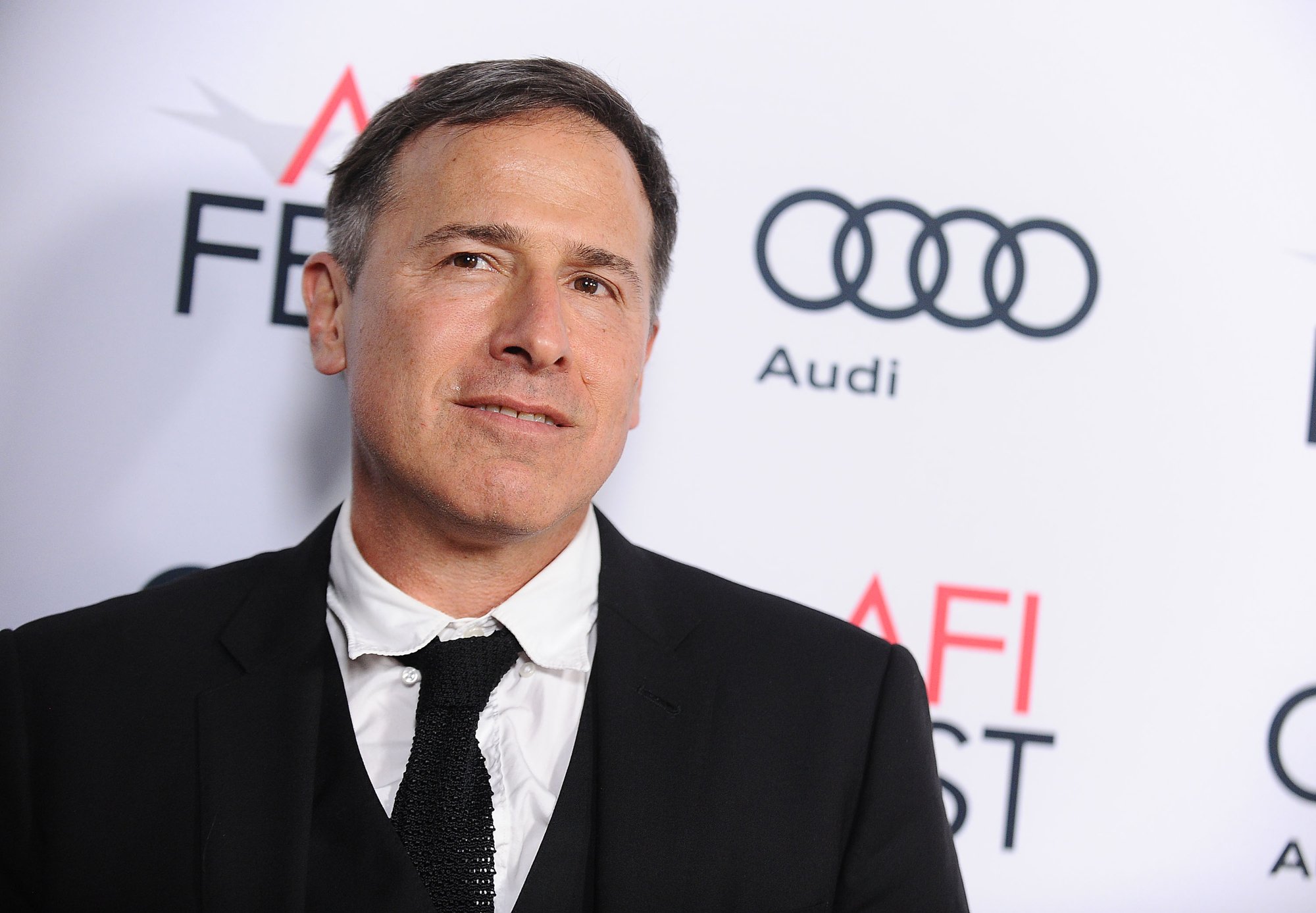 'Amsterdam' filmmaker David O. Russell wearing a suit with a slight smile in front of AFI Fest step and repeat