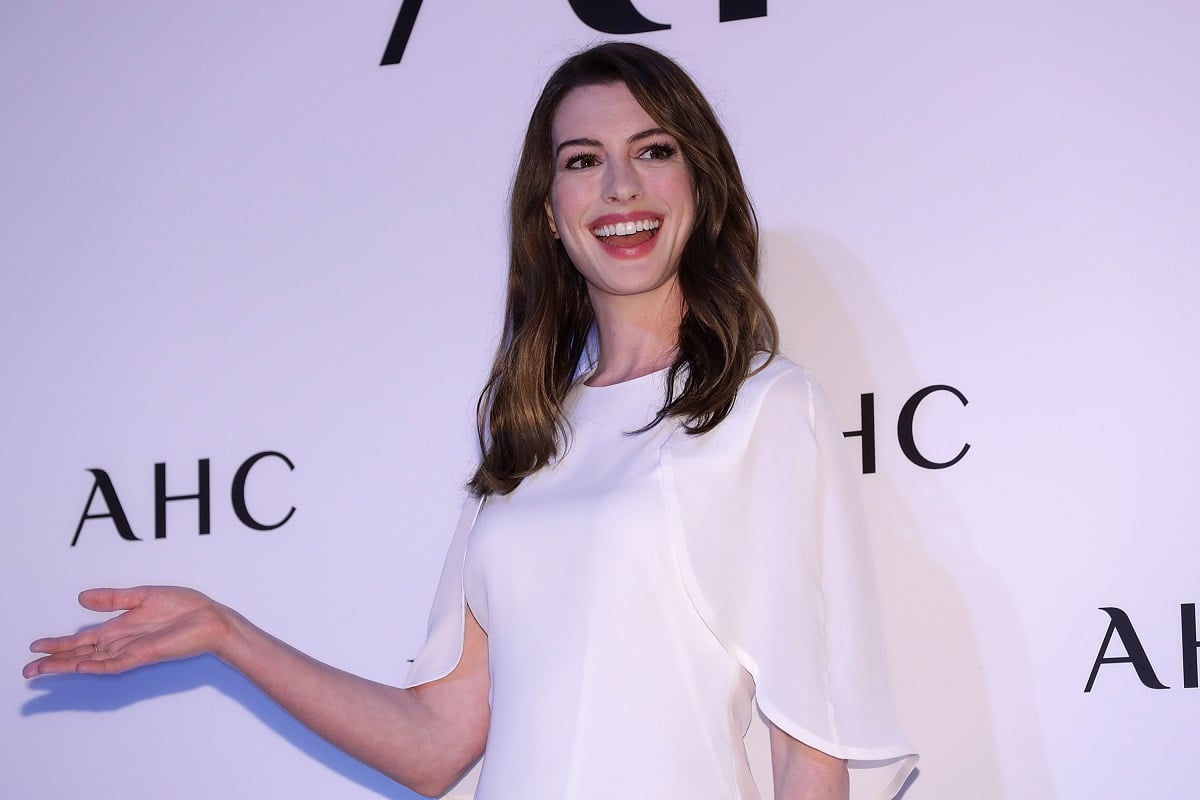 Anne Hathaway smiling while wearing a white dress.