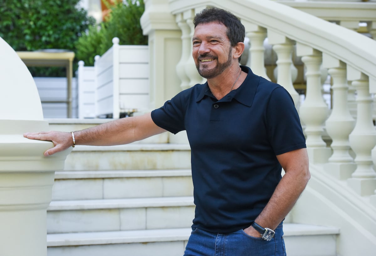 Antonio Banderas smiling, leaning on a staircase railing