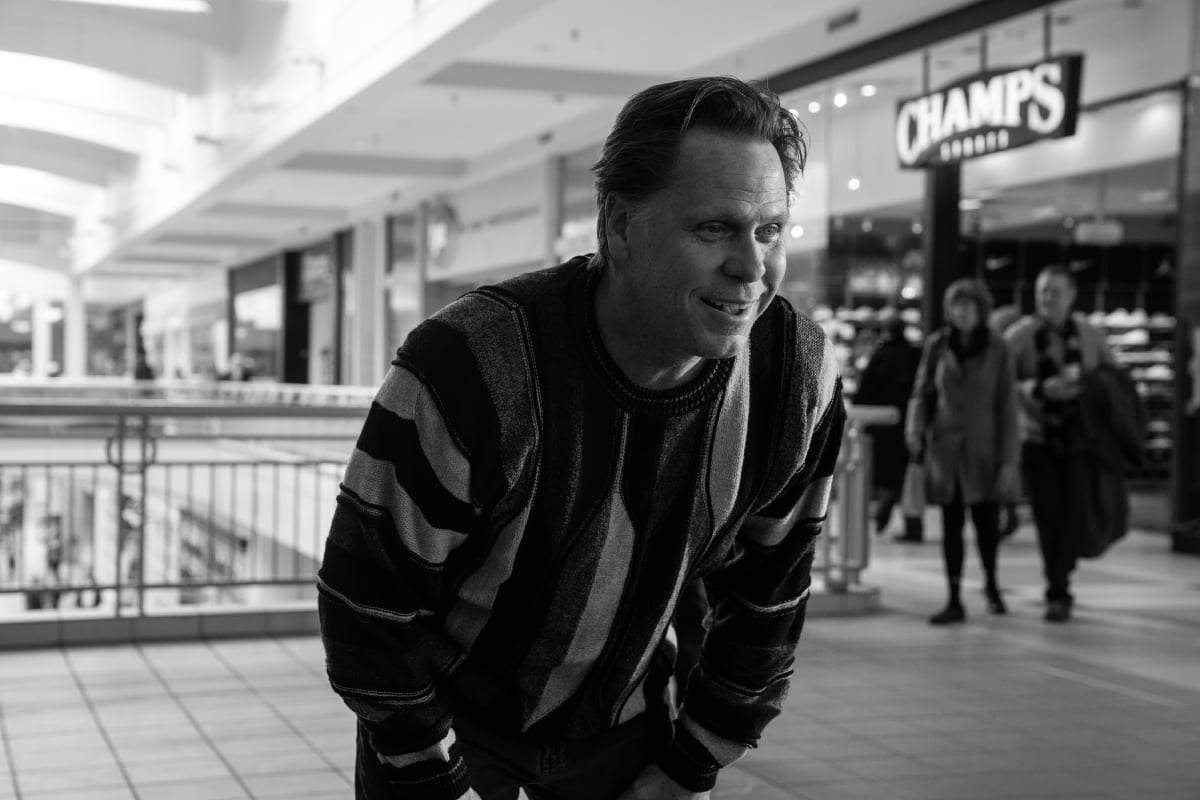 Don Harvey as Jeff the Cabbie in Better Call Saul Season 5. Jeff crouches forward at the mall wearing a striped sweater.