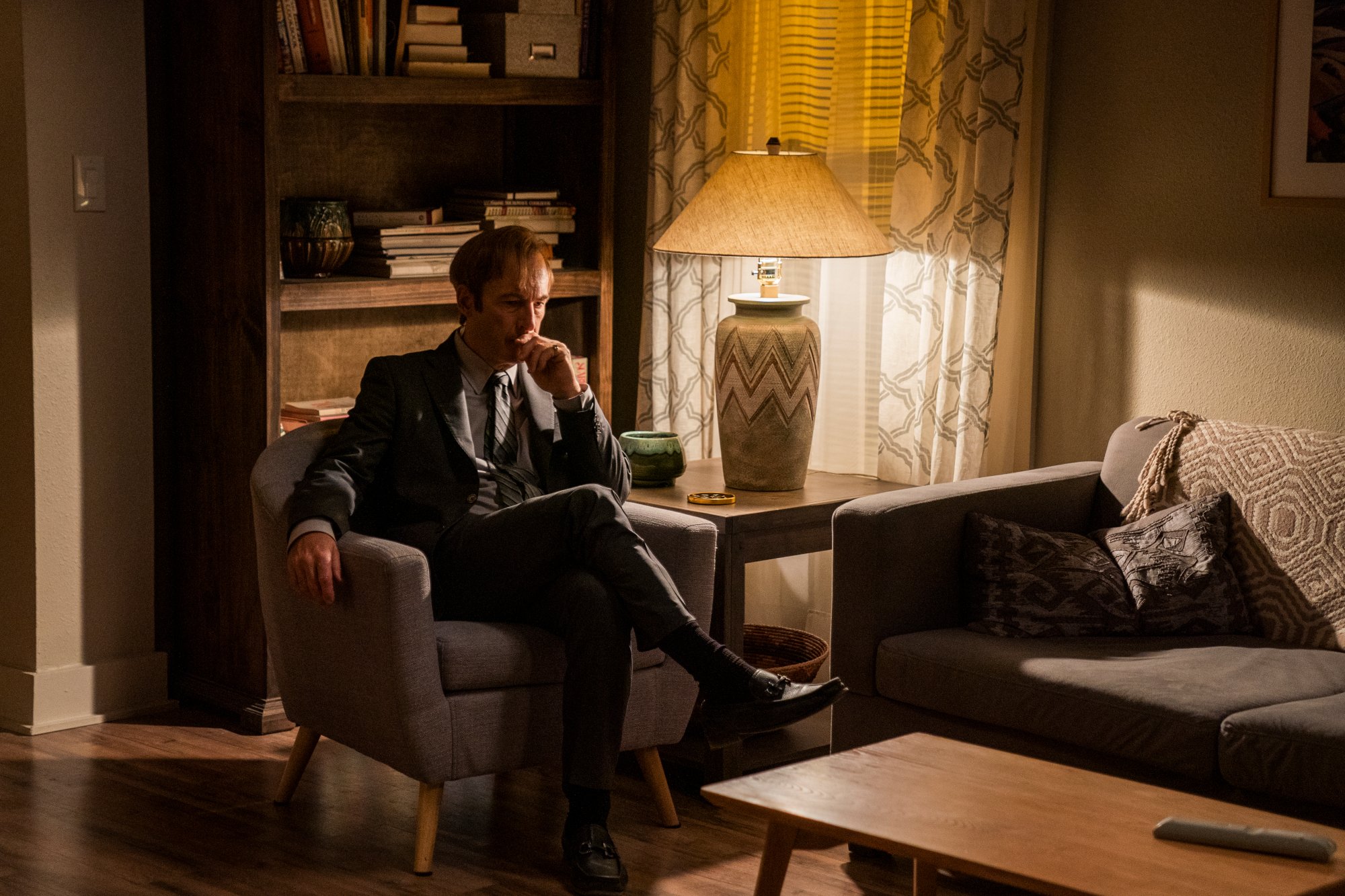 Bob Odenkirk as Saul Goodman in 'Better Call Saul' Season 6 Episode 9. He's sitting in a chair and looks contemplative.