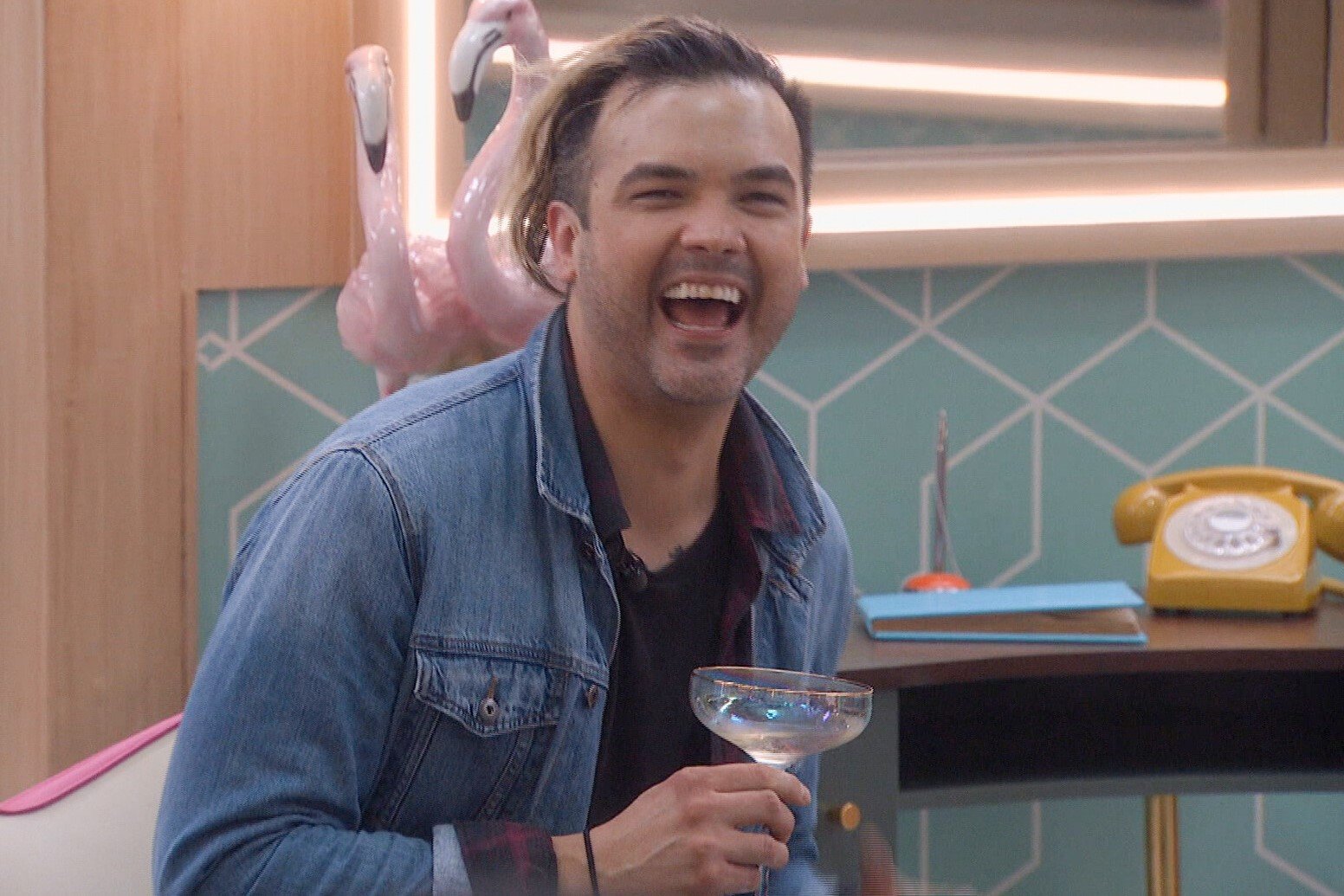 Daniel Durston, who is one of the 'Big Brother 24' houseguests, wears a jean jacket over a black shirt and holds a cocktail glass.