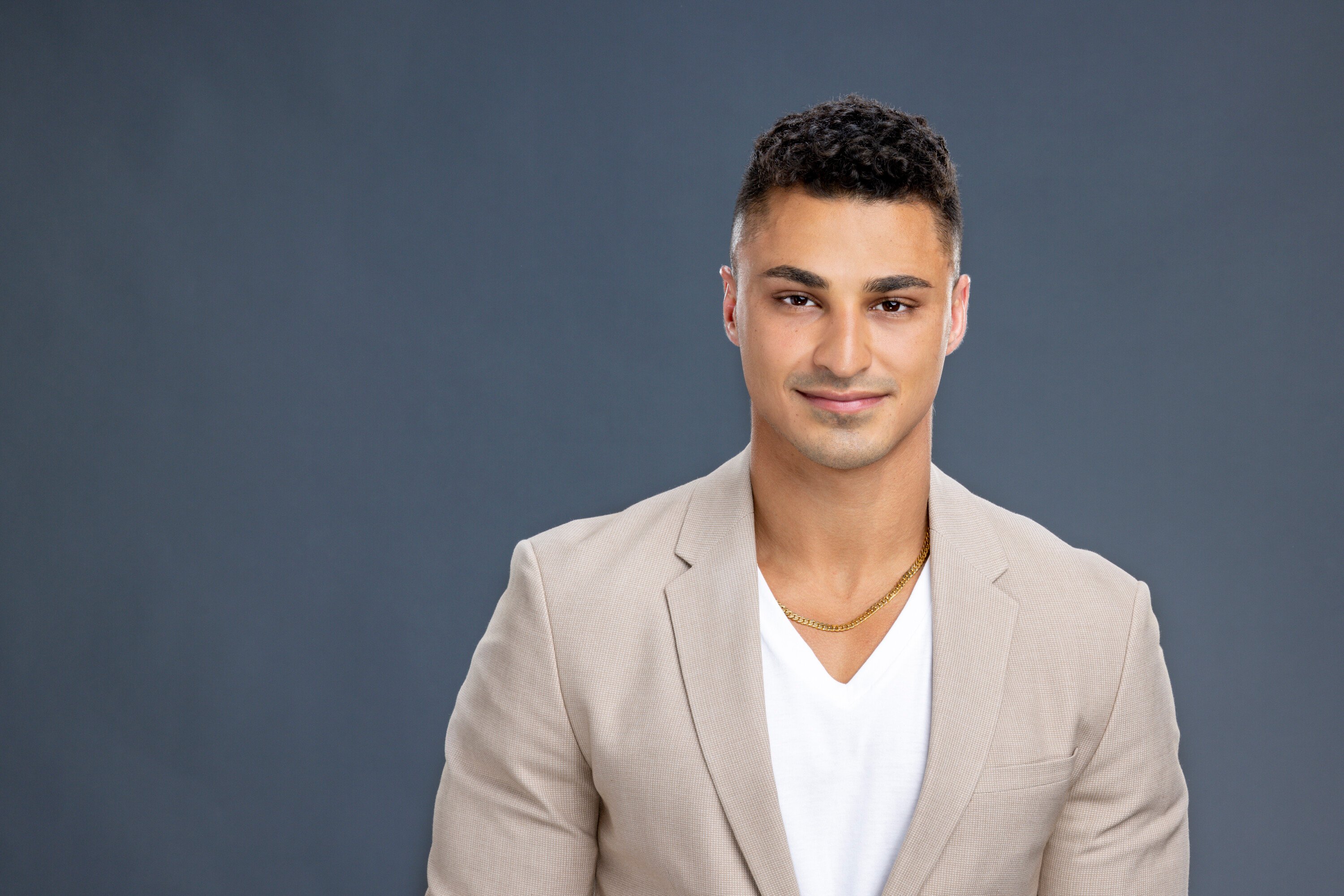 Joseph Abdin, who replaced Marvin in 'Big Brother' Season 24, wears a light tan suit over a white v-neck shirt and gold chain.