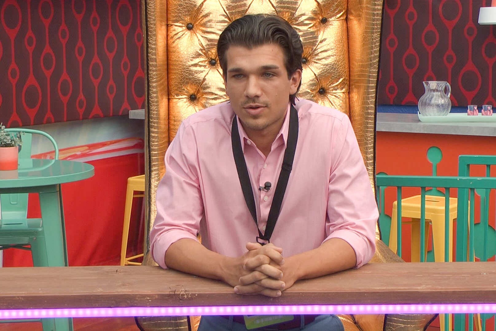 Joe 'Pooch' Pucciarelli, who is the Backstage Boss on 'Big Brother' Season 24, wears a pink button-up shirt and a backstage pass around his neck.