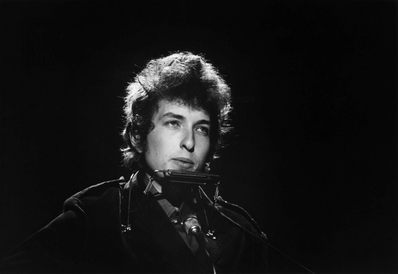 A black and white picture of Bob Dylan with a harmonica.