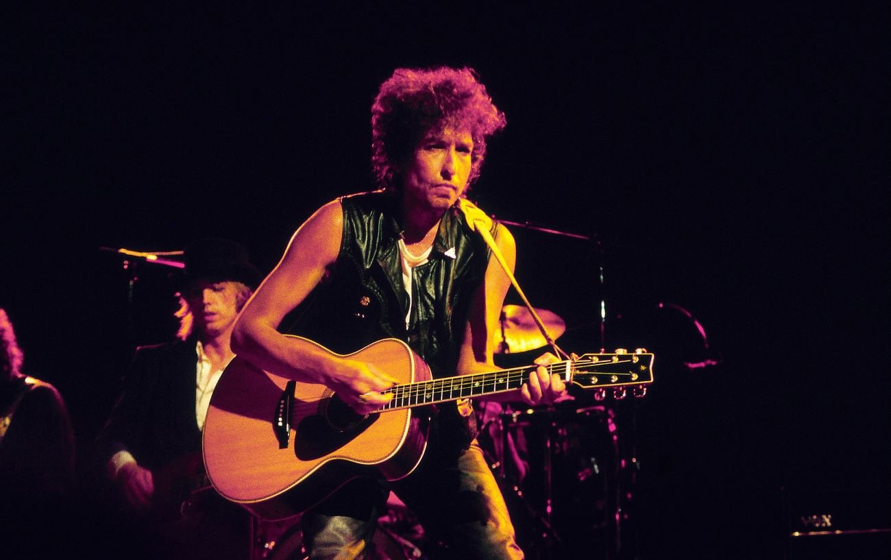 Bob Dylan wears a vest and plays guitar while on tour.