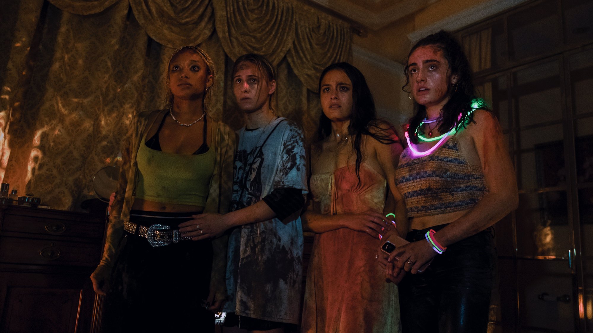 'Bodies Bodies Bodies' Amandla Stenberg as Sophie, Maria Baklava as Bee, Chase Sui Wonders as Emma, and Rachel Sennott as Alice looking terrified with distressed clothes and gold curtains behind them
