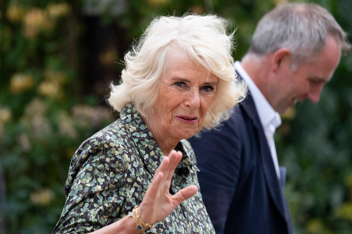 Camilla Parker Bowles, who a body language expert says is no longer nervous about how she's received, waves to the crowd after visiting a residential farm