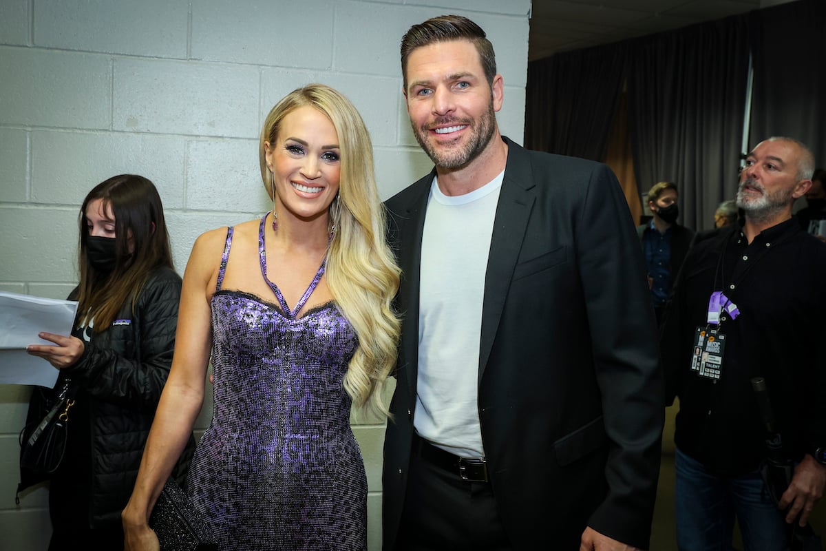 Carrie Underwood and Mike Fisher smile and pose together at an event.