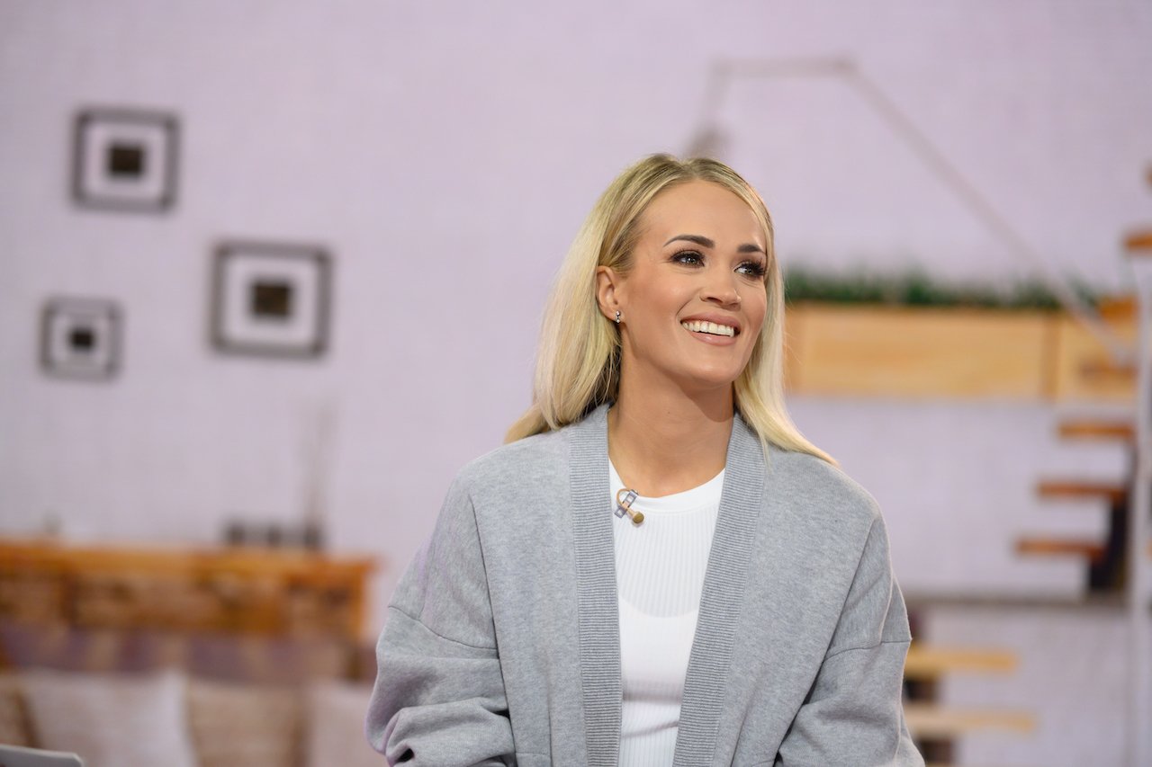 Carrie Underwood, shown in a gray cardigan and white t-shirt, shops small for produce