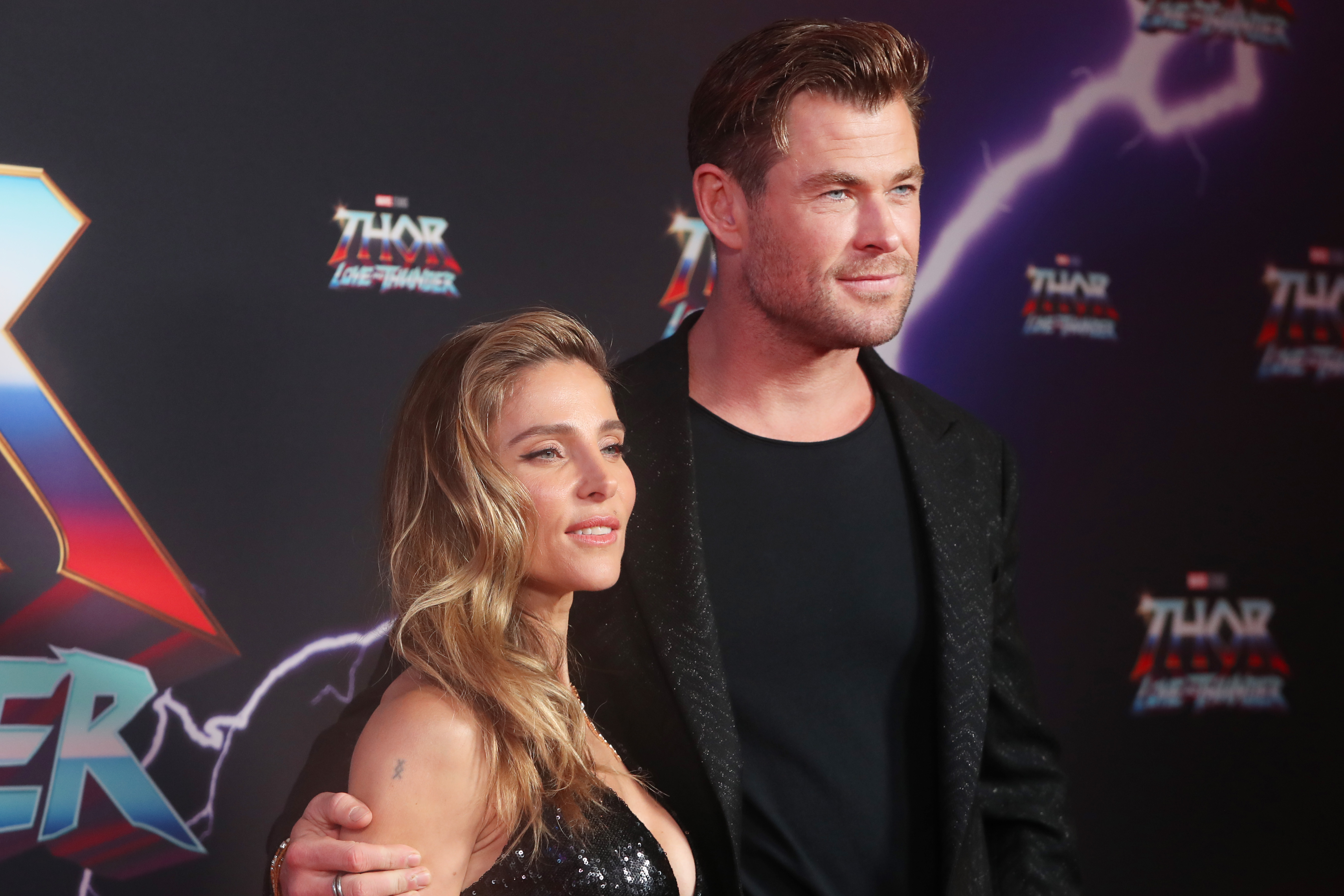 Chris Hemsworth and Elsa Pataky attend the premiere of 'Thor: Love and Thunder.' Hemsworth wears a black suit over a black shirt. Pataky wears a black sequin dress.