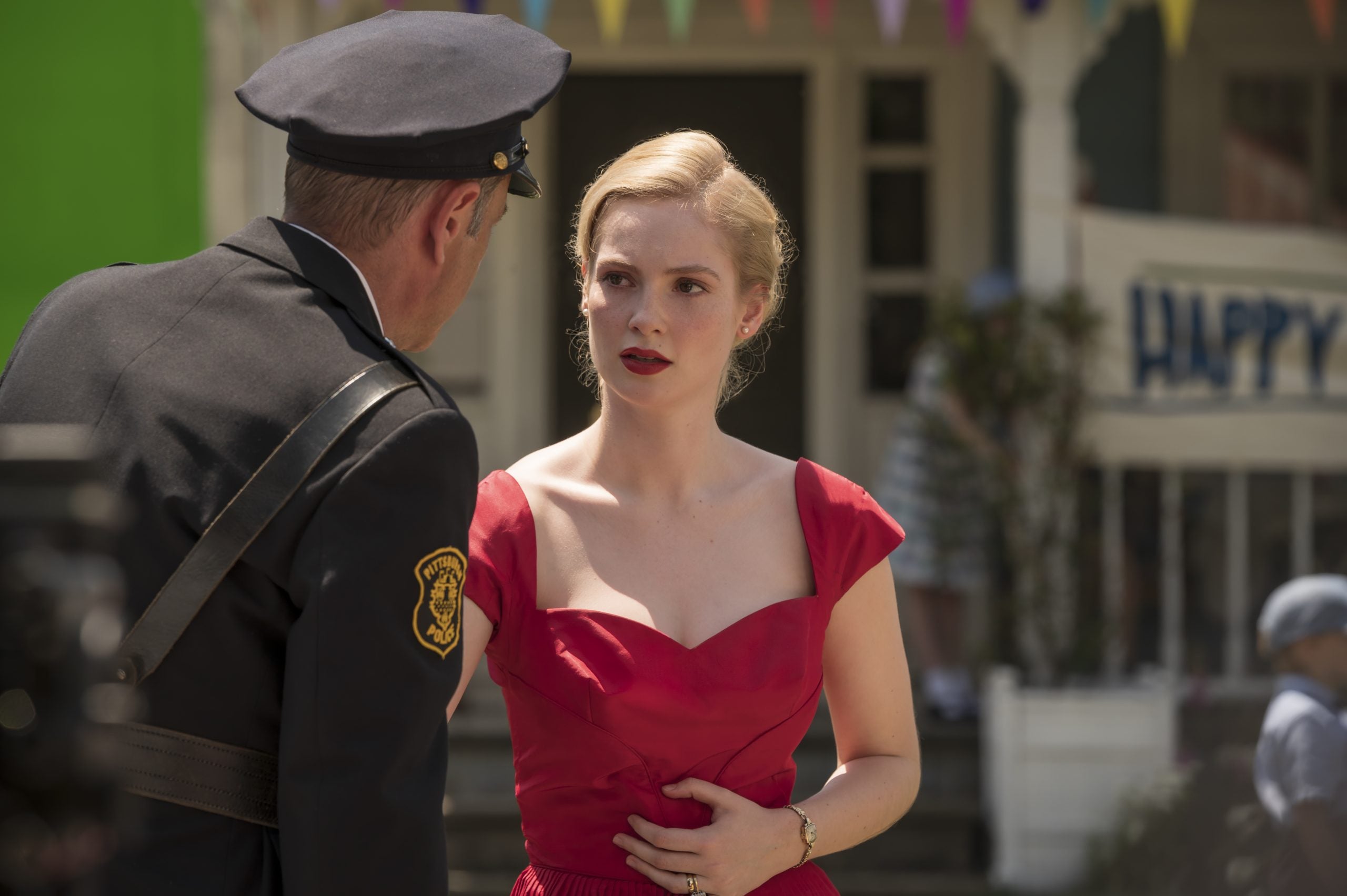 Hannah Dodd as Corrine, wearing a red dress and talking to a police officer, in 'Flowers in the Attic: The Origin'