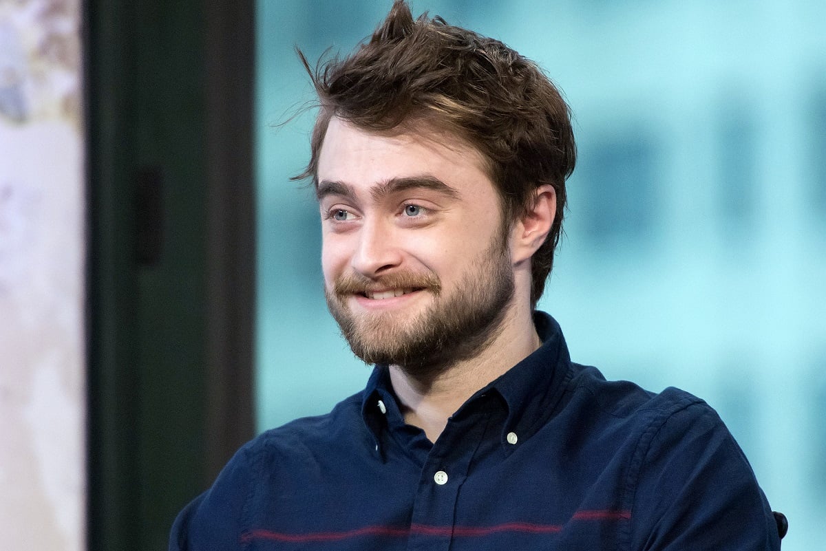 Daniel Radcliffe smiling while wearing a dark blue shirt.