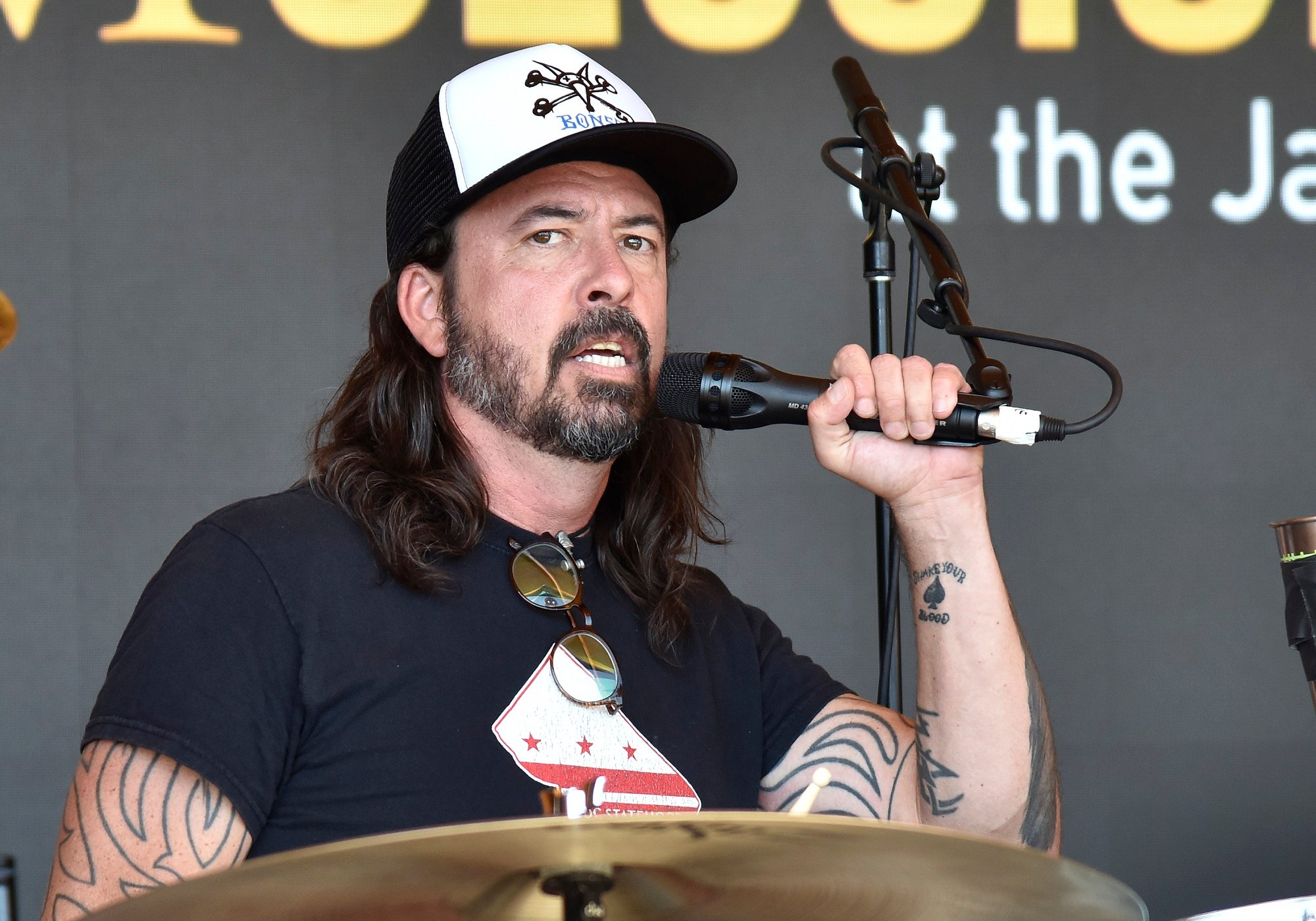 Foo Fighters' Dave Grohl holding a microphone and wearing a hat and black T-shirt