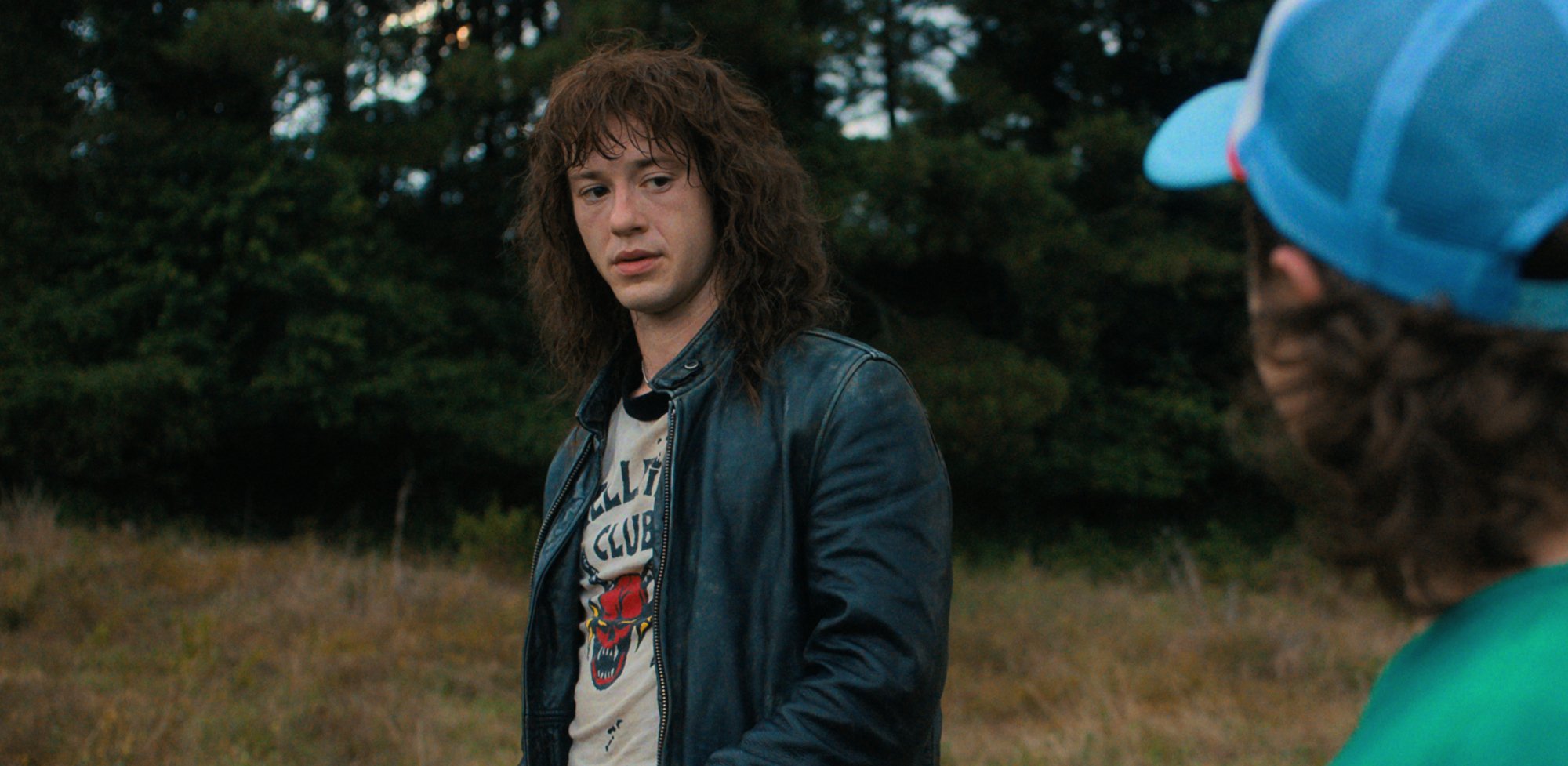Eddie Munson, who could return as Kas in 'Stranger Things' 5, wearing a leather jacket and looking at Dustin.